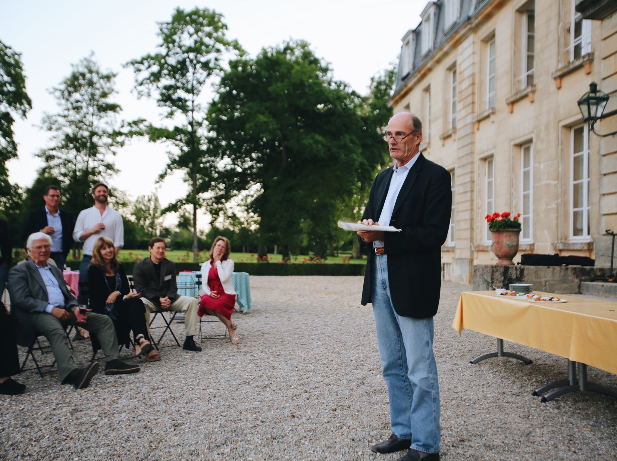 A man leading a group discussion in front of the chateau during corporate team building activities at Courtomer in Normandy.