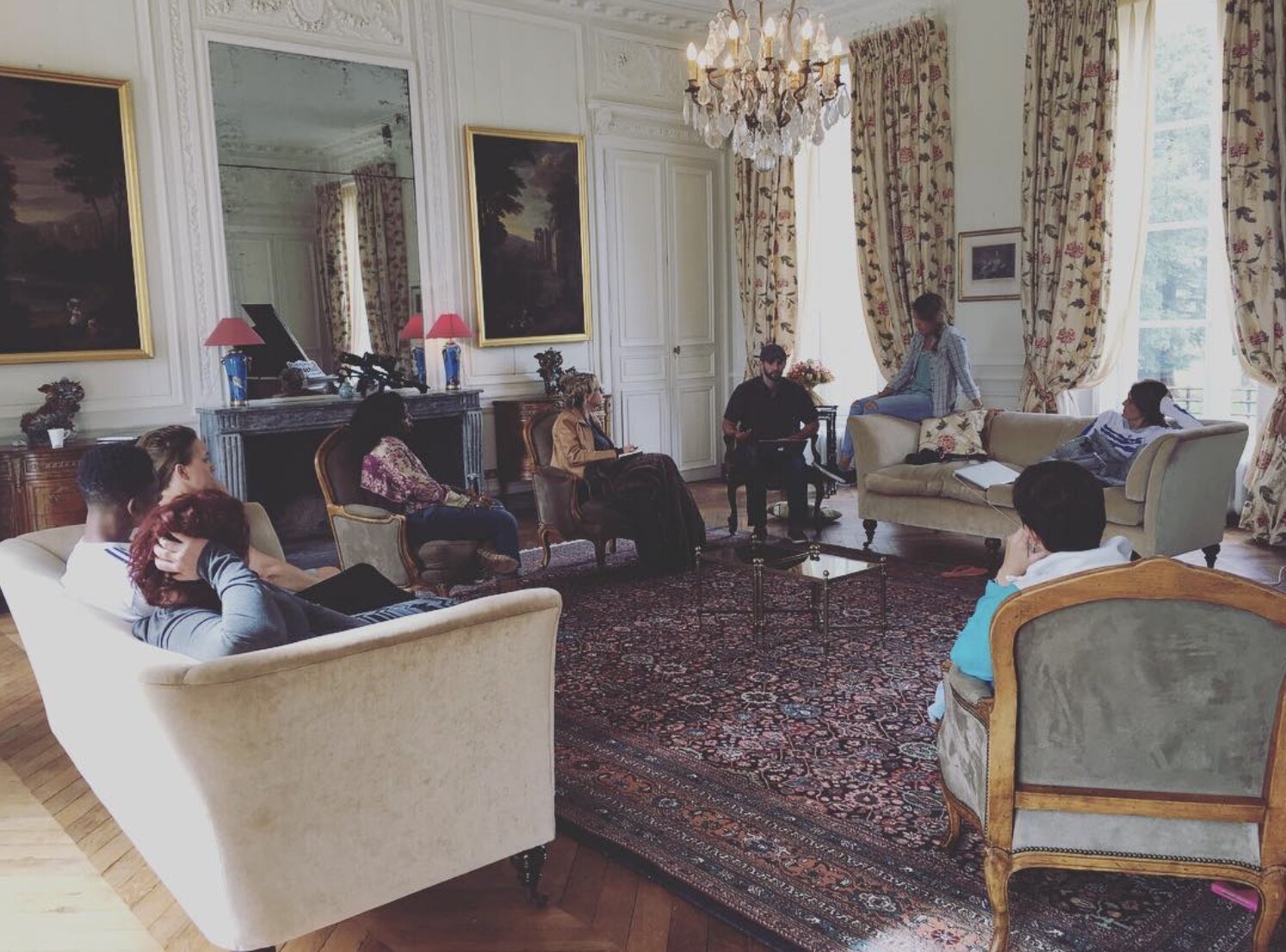A group of people sitting in a large living room at the chateau during a company retreat in Normandy, France.