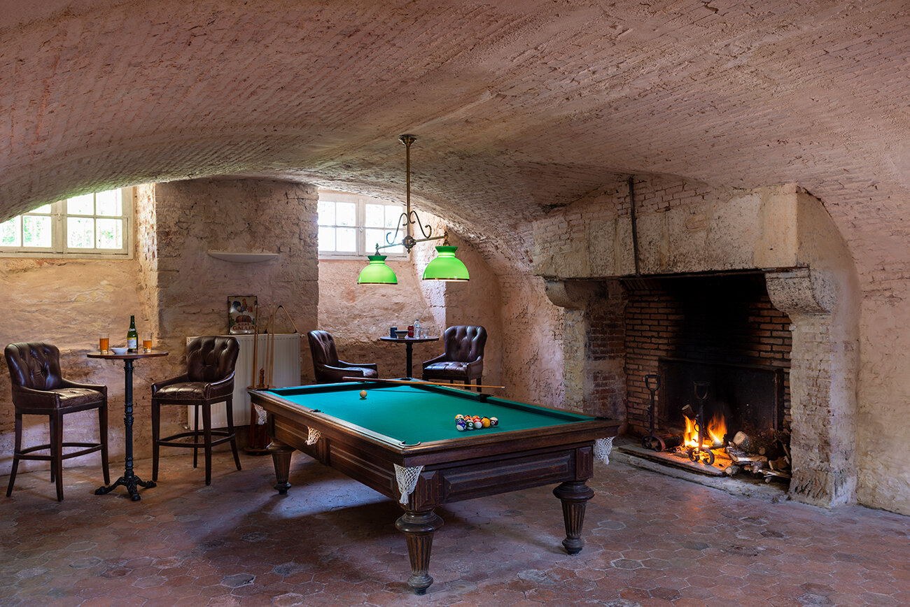 A pool table and fireplace in the games room of Chateau de Courtomer, a chateau near paris.