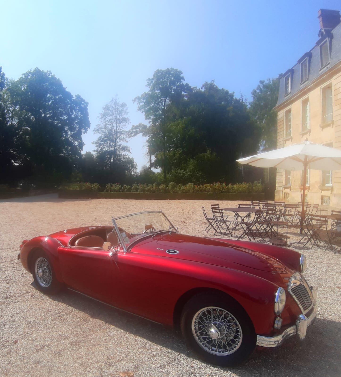 A red car parked in front of the chateau which is sometimes used for corporate and other kinds of retreats.