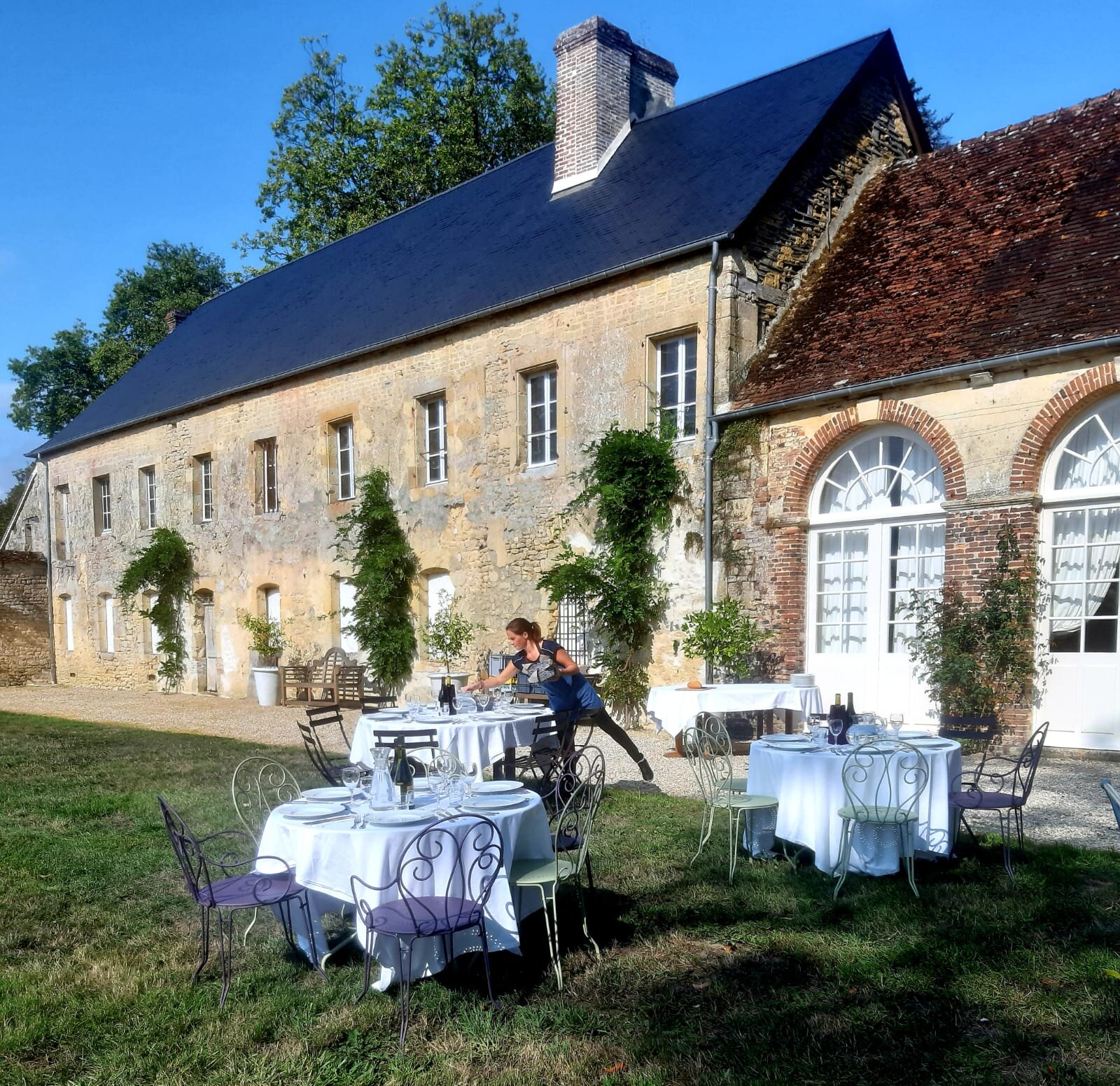 The Orangerie, a pretty brick building with tables and chairs outside, a perfect venue for retreats and functions in France.