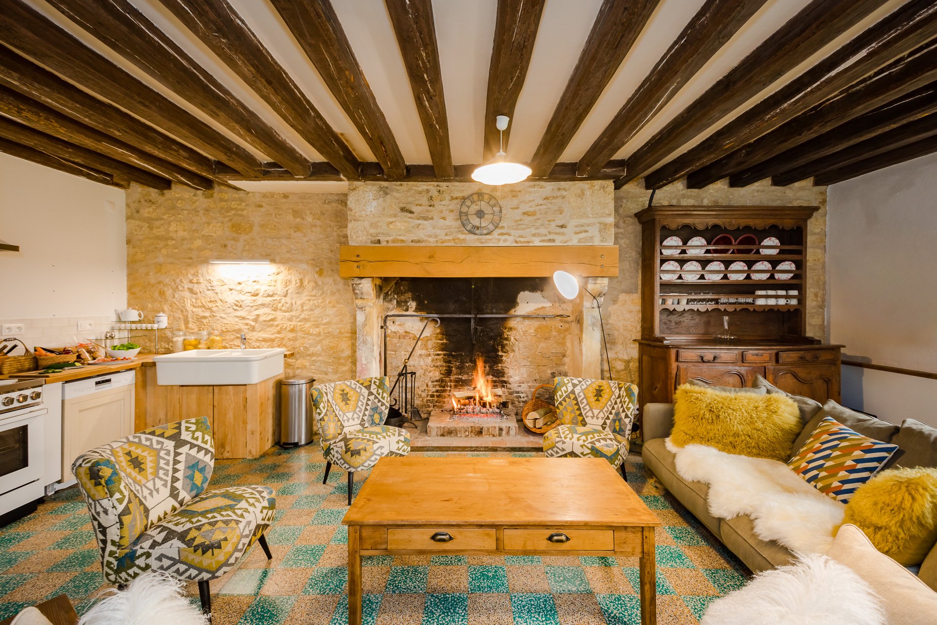 A living room with a fireplace and chairs in the Farmhouse, a cosy french cottage available for rent at Chateau de Courtomer.