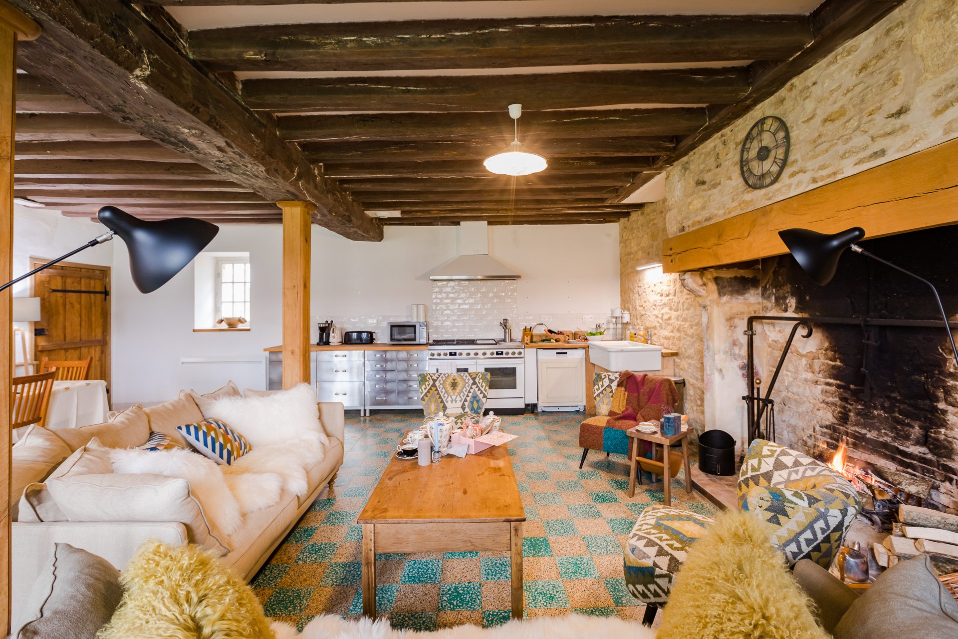 A living room with a stone fireplace and wooden beams in the farmhouse, perfect for a cozy ambiance during a holiday in france.