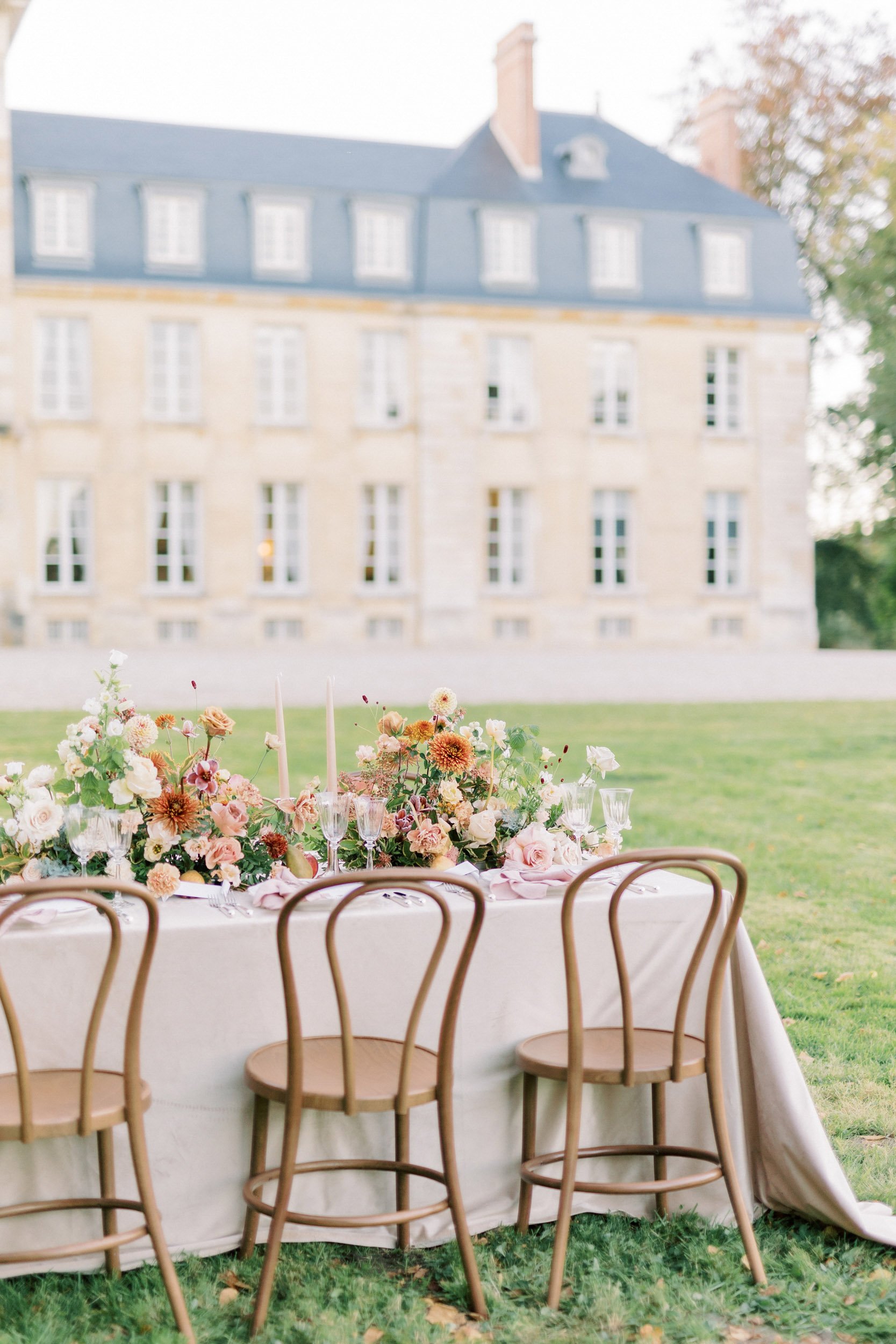 A table set up in front of a large French chateau.