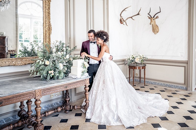 A bride and groom cutting their wedding cake in a picturesque French chateau near Paris on their wedding day.