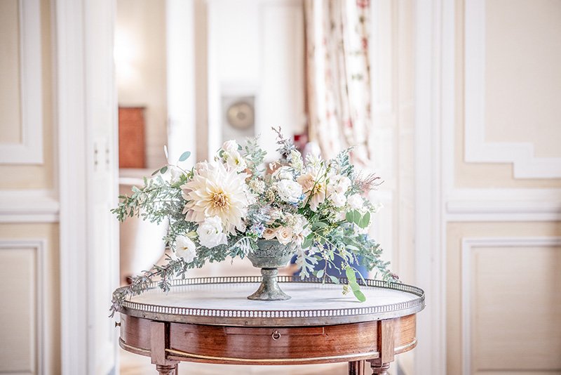 An ornate side table with a pastel, intricate floral decoration in the hallway of Chateau de Courtomer.