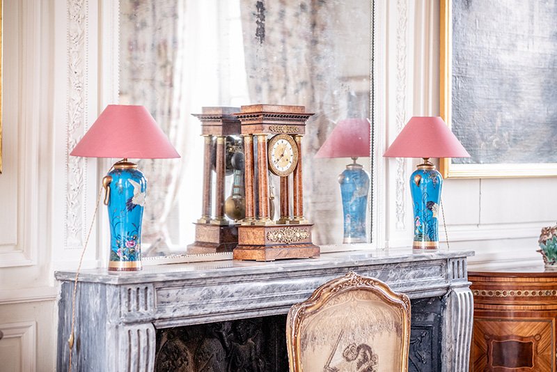 A closeup of a marble fireplace and antique clock in the sitting room of Chateau de Courtomer.