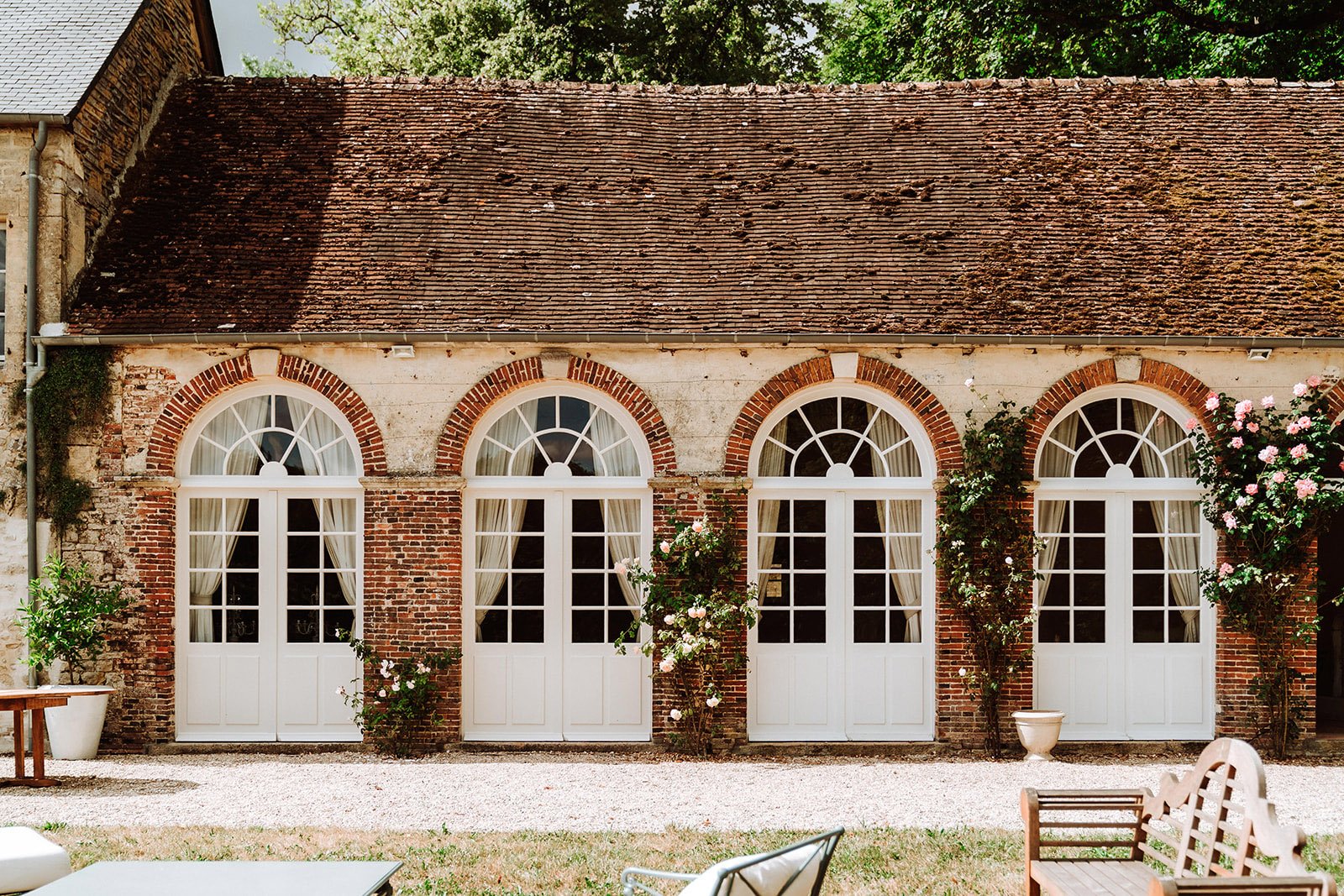 The Orangerie from the outside covered with climbing roses perfect for barbeques and al fresco dining available for rent in France.