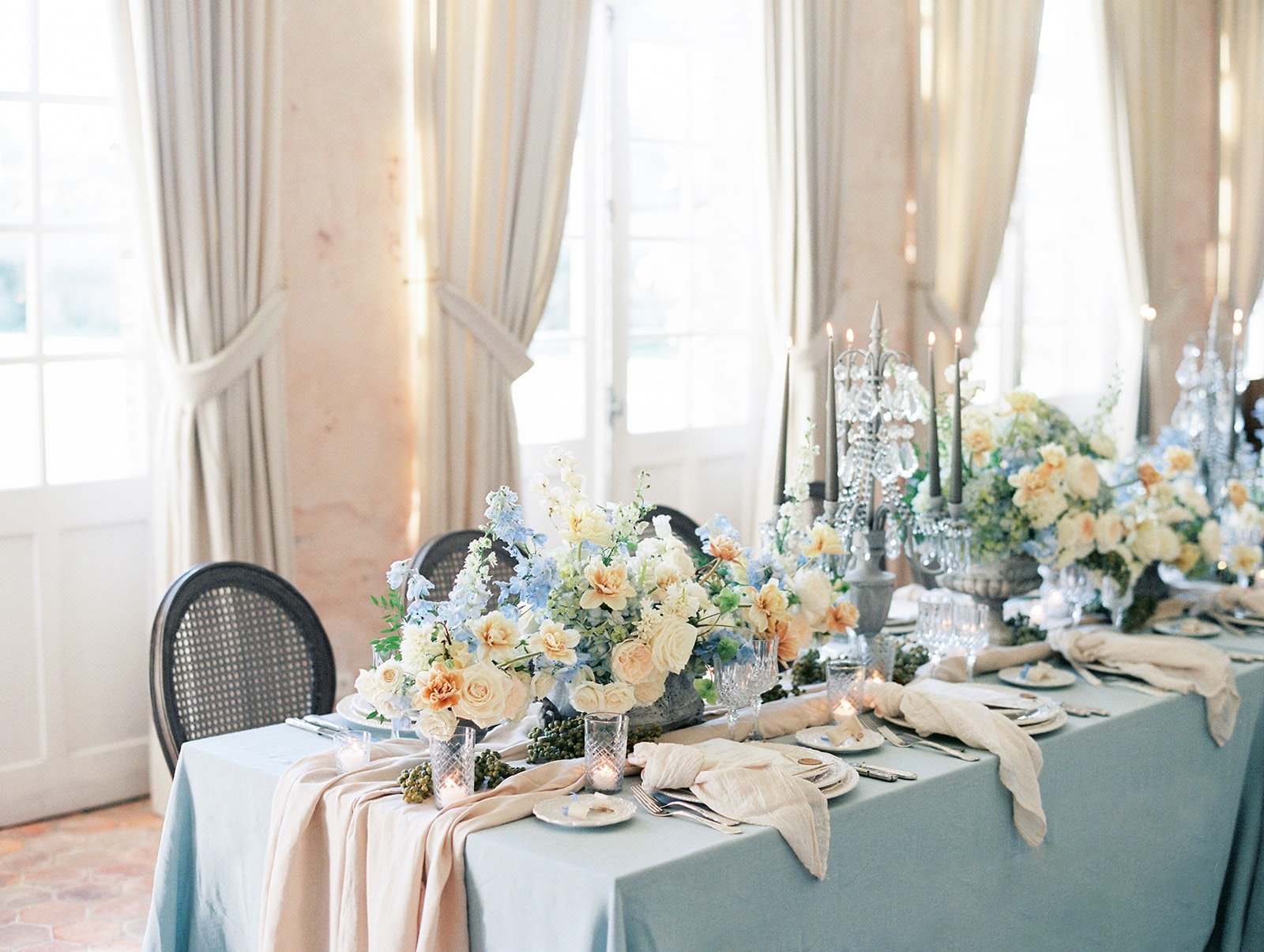 A table adorned with blue and white flowers at a chateau near Paris for a wedding.
