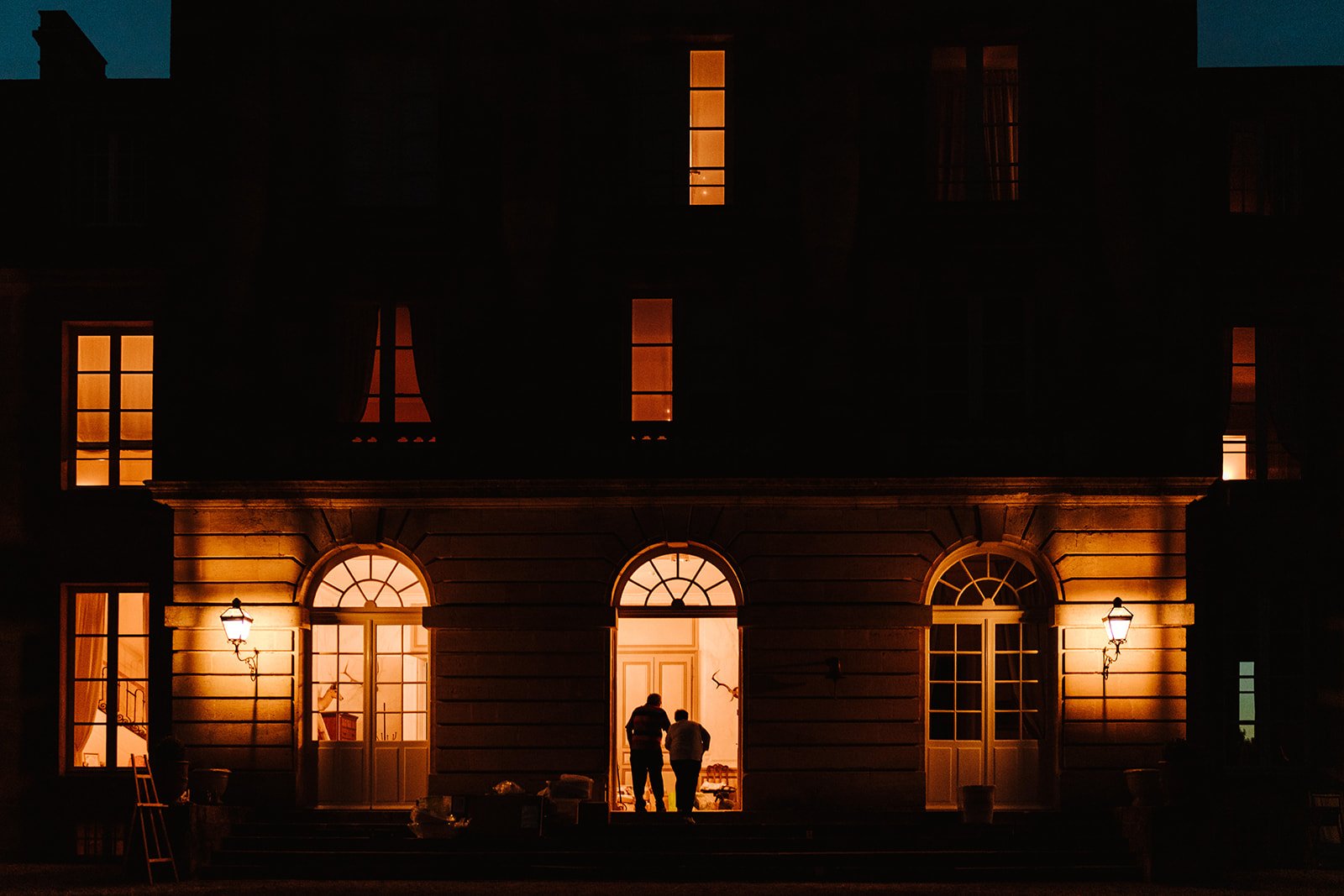 People silhouetted on the steps of the Chateau at night.