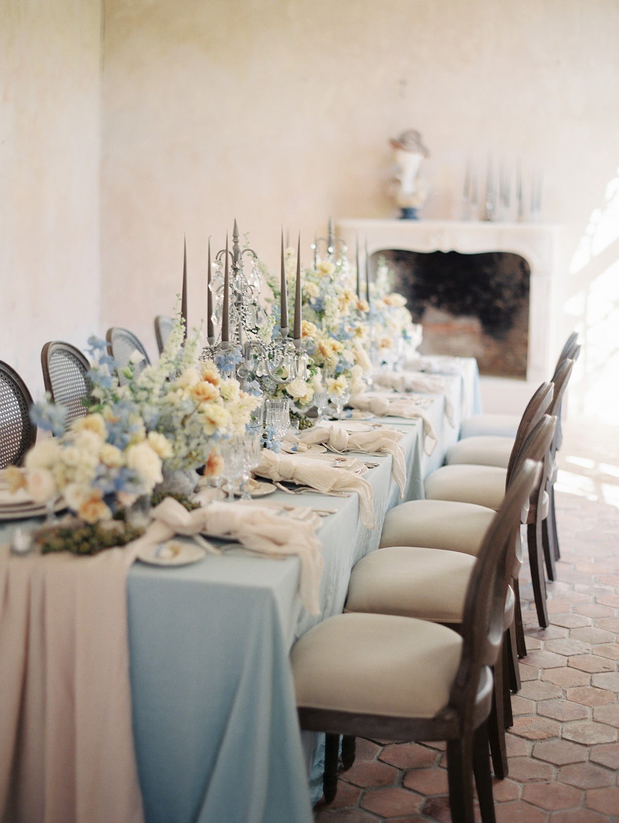 A table set for a wedding breakfast featuring  blue and white linens and pastel floral decorations at Chateau de Courtomer, a French chateau wedding venue in Normandy.