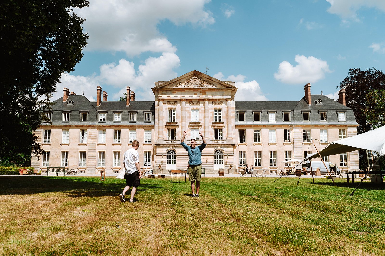 Two men enjoying a lawn game in front of a Chateau de Courtomer, a large French chateau for rent in Normandy.