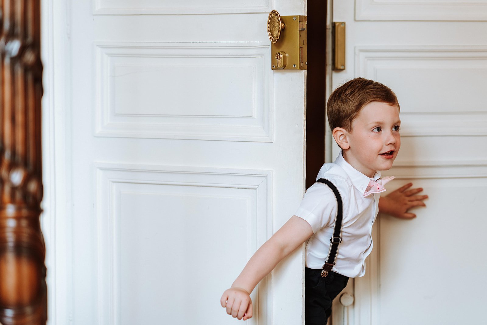 A little boy peeking out of an open door inside the chateau.
