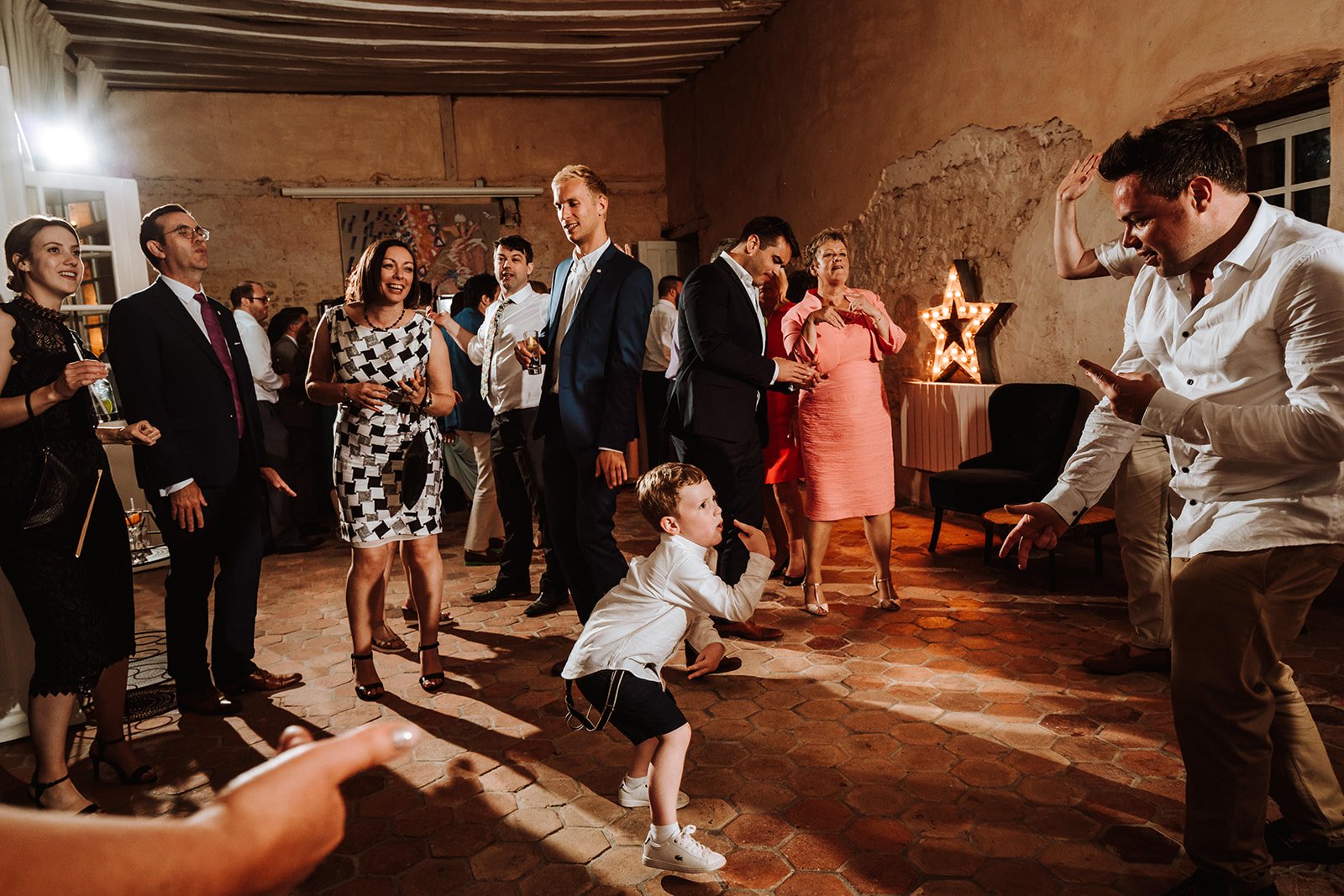 A little boy is dancing in the middle of a group of people during a chateau wedding  in France.