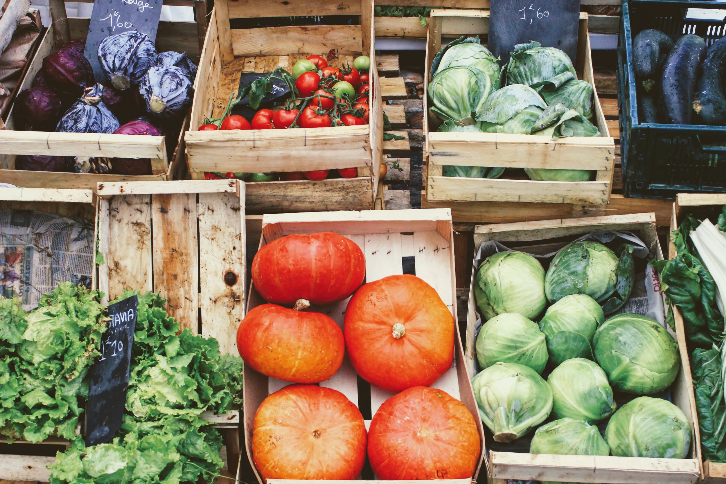 A variety of fresh vegetables are displayed in wooden crates.