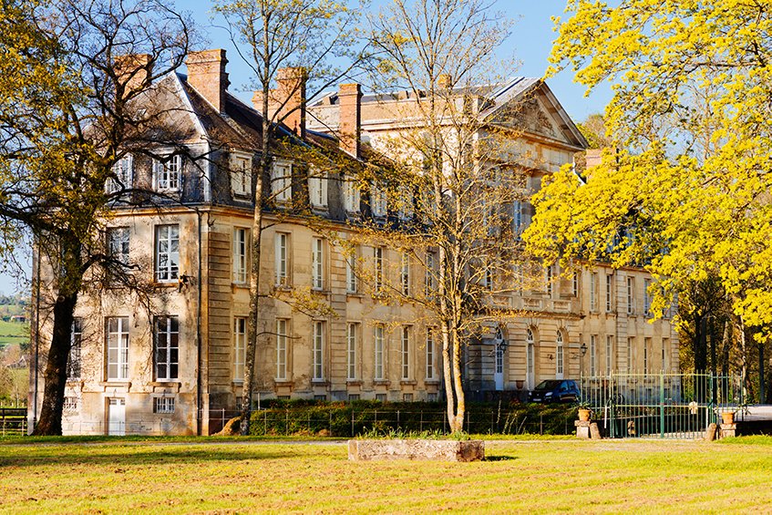 A grand chateau surrounded by a vast grassy field, perfect for weekend getaways in France.