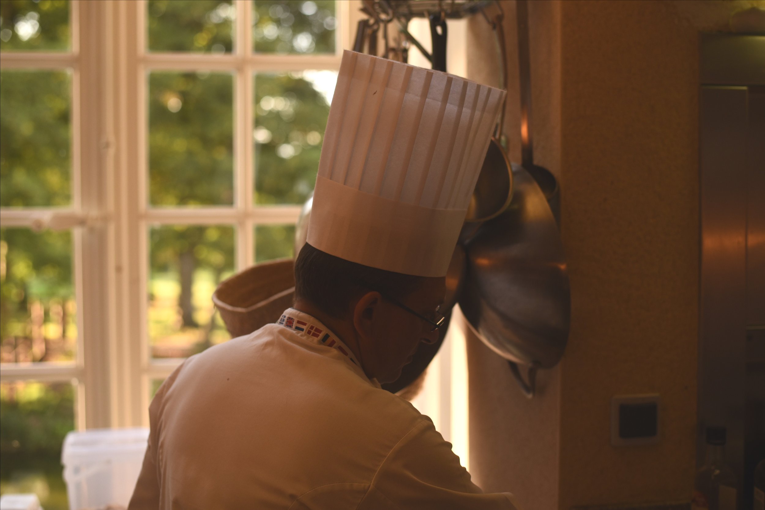 A chef wearing a tall white toque hat in the kitchenat Chateau de Courtomer, Normandy