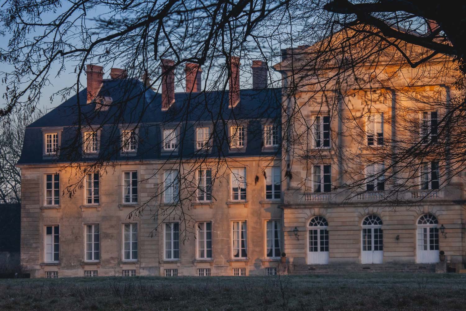 Dusk falls on the honey coloured  facade of Chateau de Courtomer, available to rent for farmily reunions