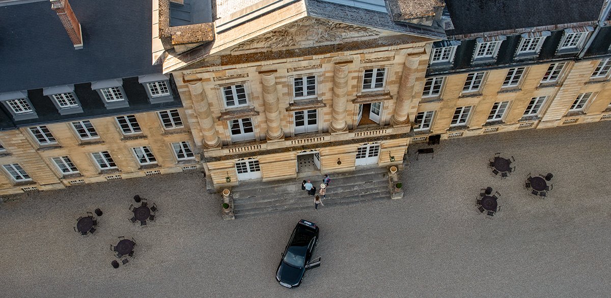 An aerial view of a car dropping guests off in front of Chateau de Courtomer.