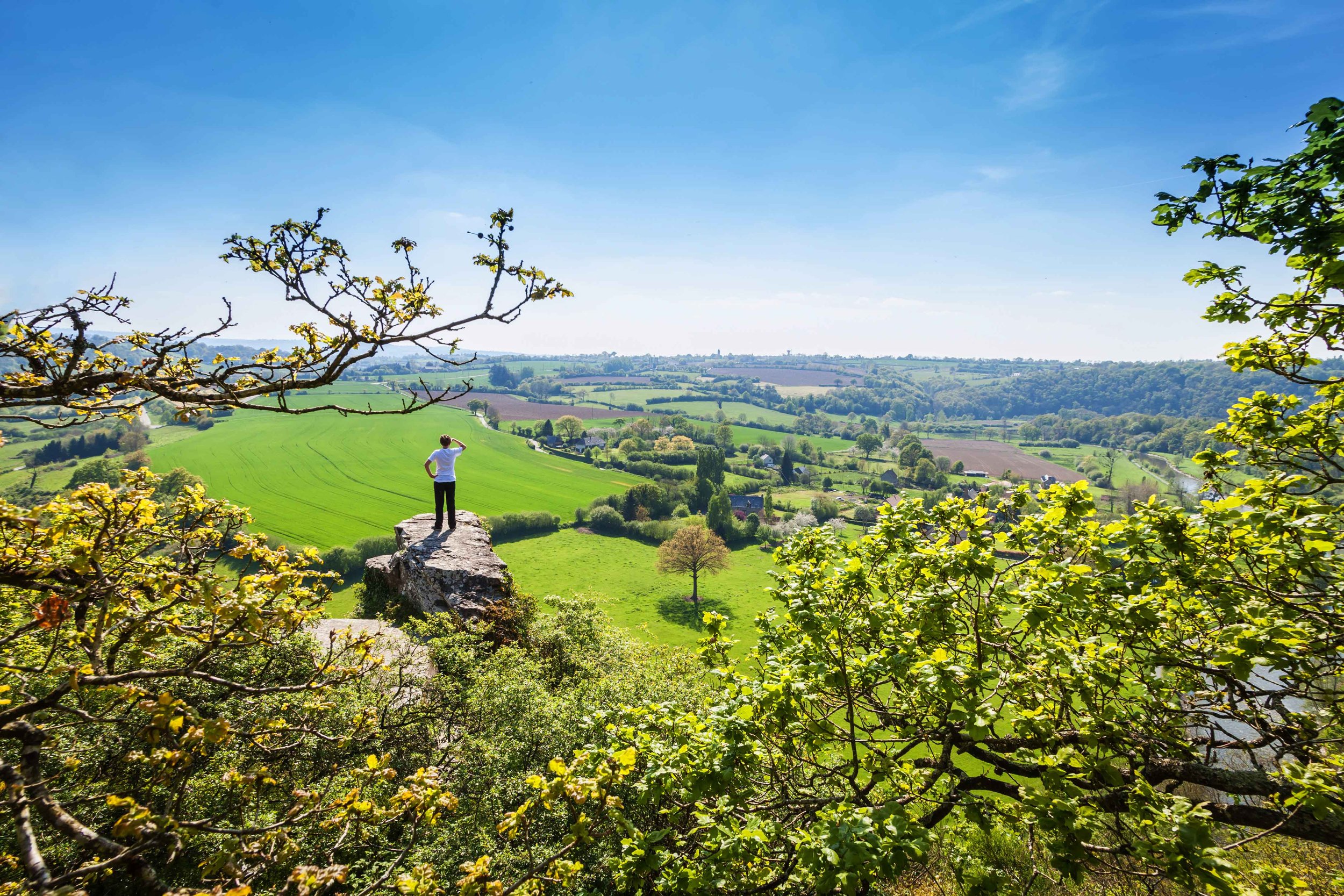 A man standing on top of a hill overlooking a valley in Normandy, France.