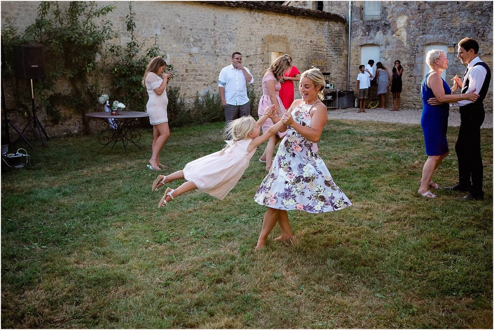 A woman and her daughter are playing  in the walled garden at a French chateau wedding.
