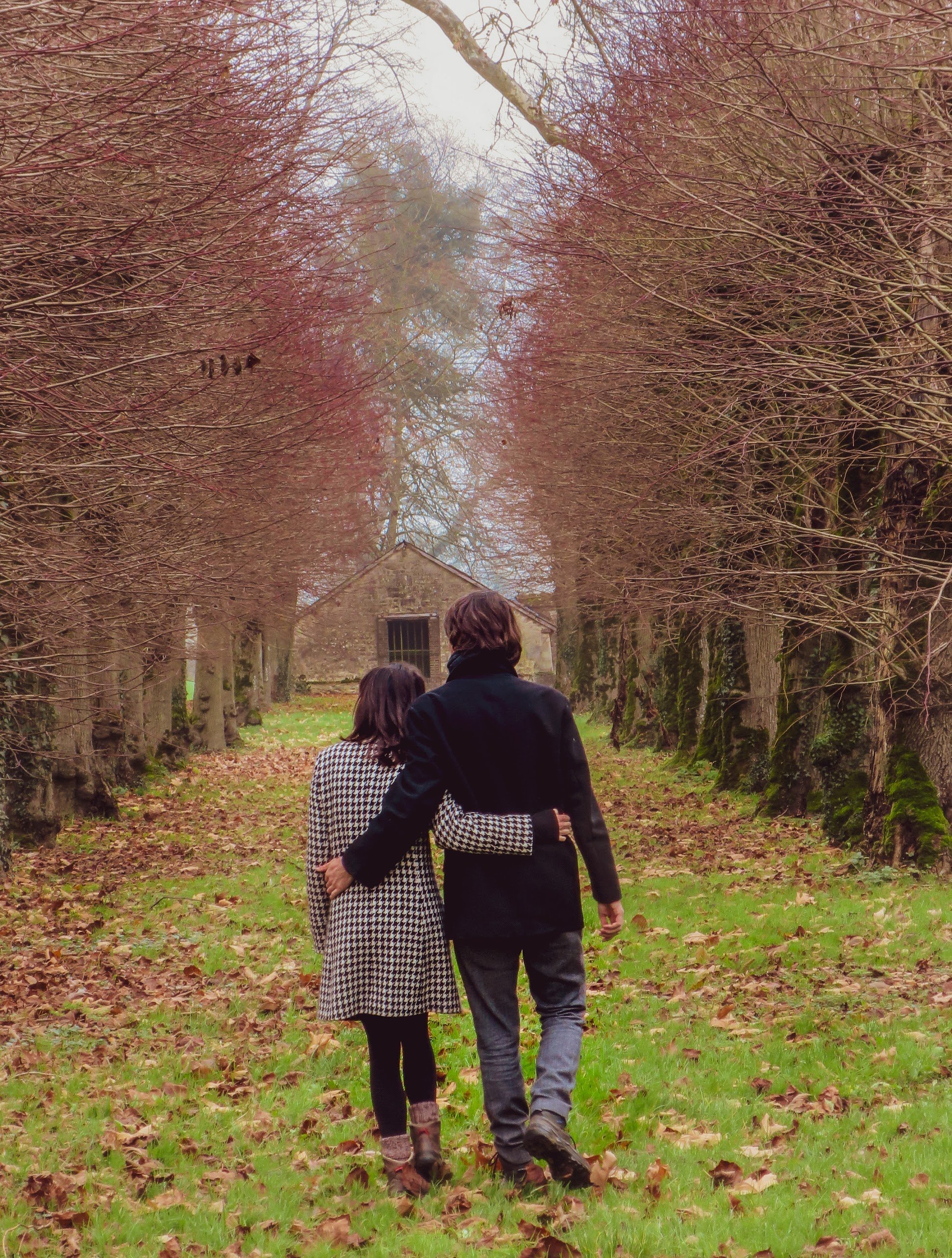 A couple strolling down the Linden Alley in Autumn during their French chateau holiday.