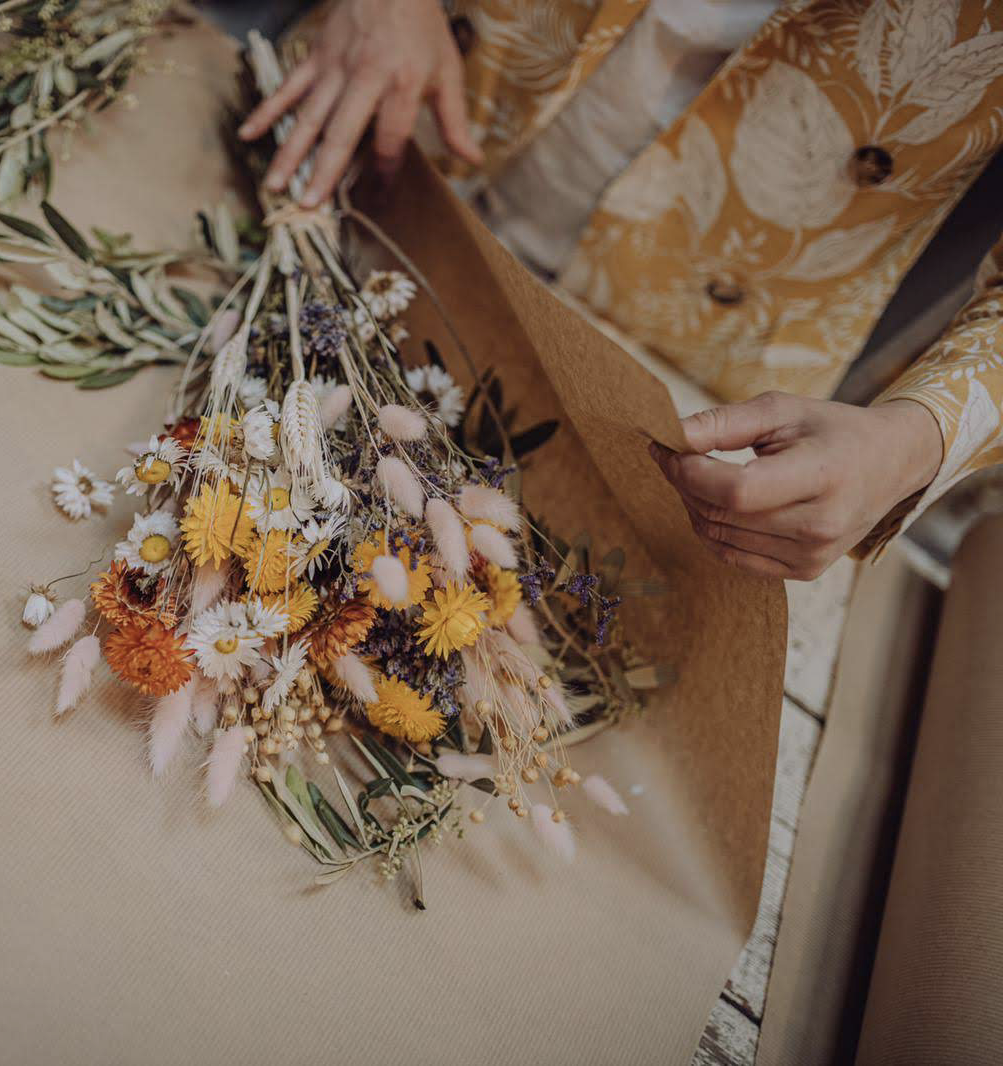 At Chateau de Courtomer, a woman skillfully arranges a bouquet of dried flowers.