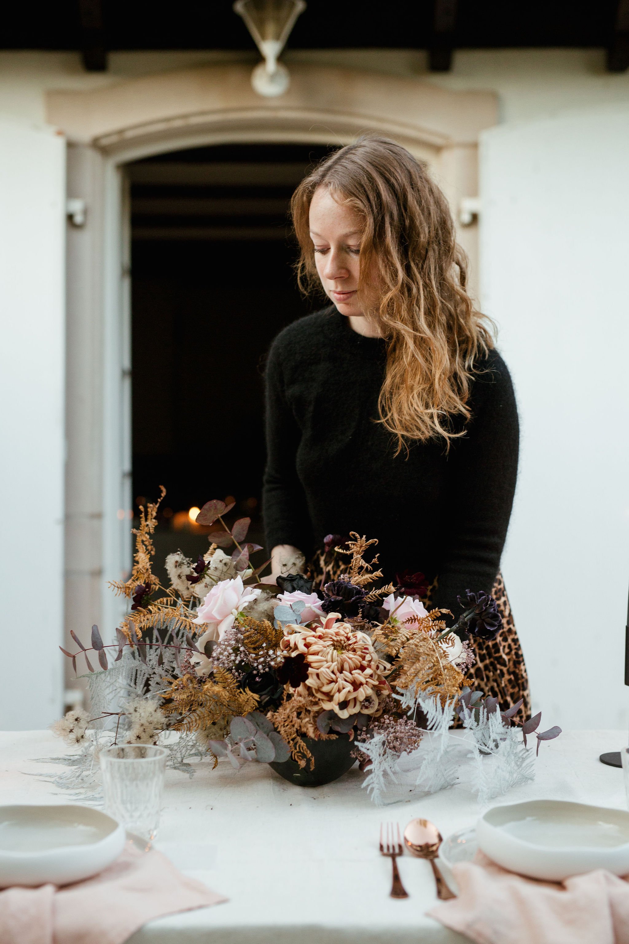 A wedding planner arranging flowers on a table at Chateau de Courtomer.