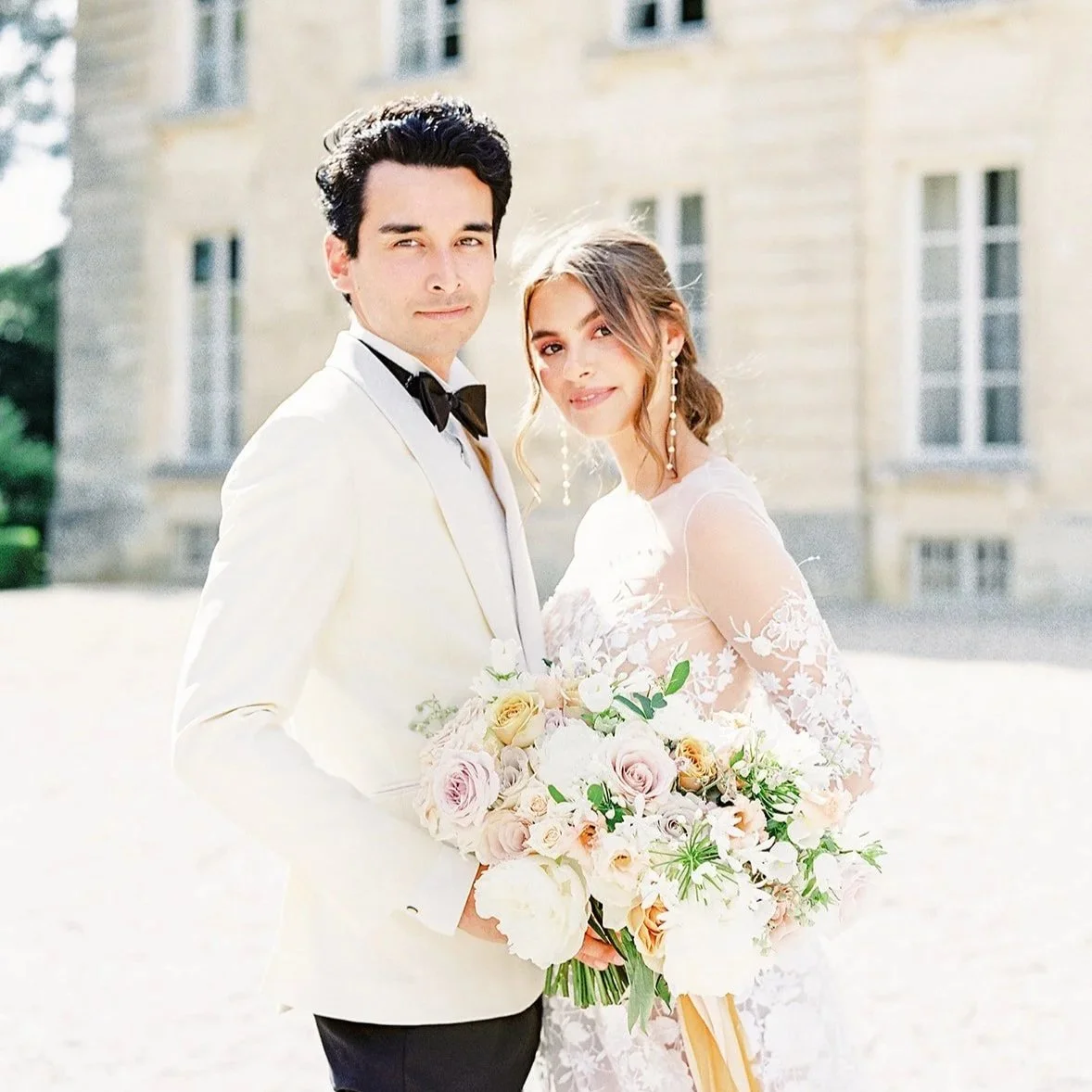 Beautiful bride holding a bouquet and her groom in front of chateau de courtomer