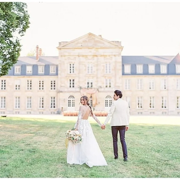 Bride and groom holding hands in front of chateau de courtomer