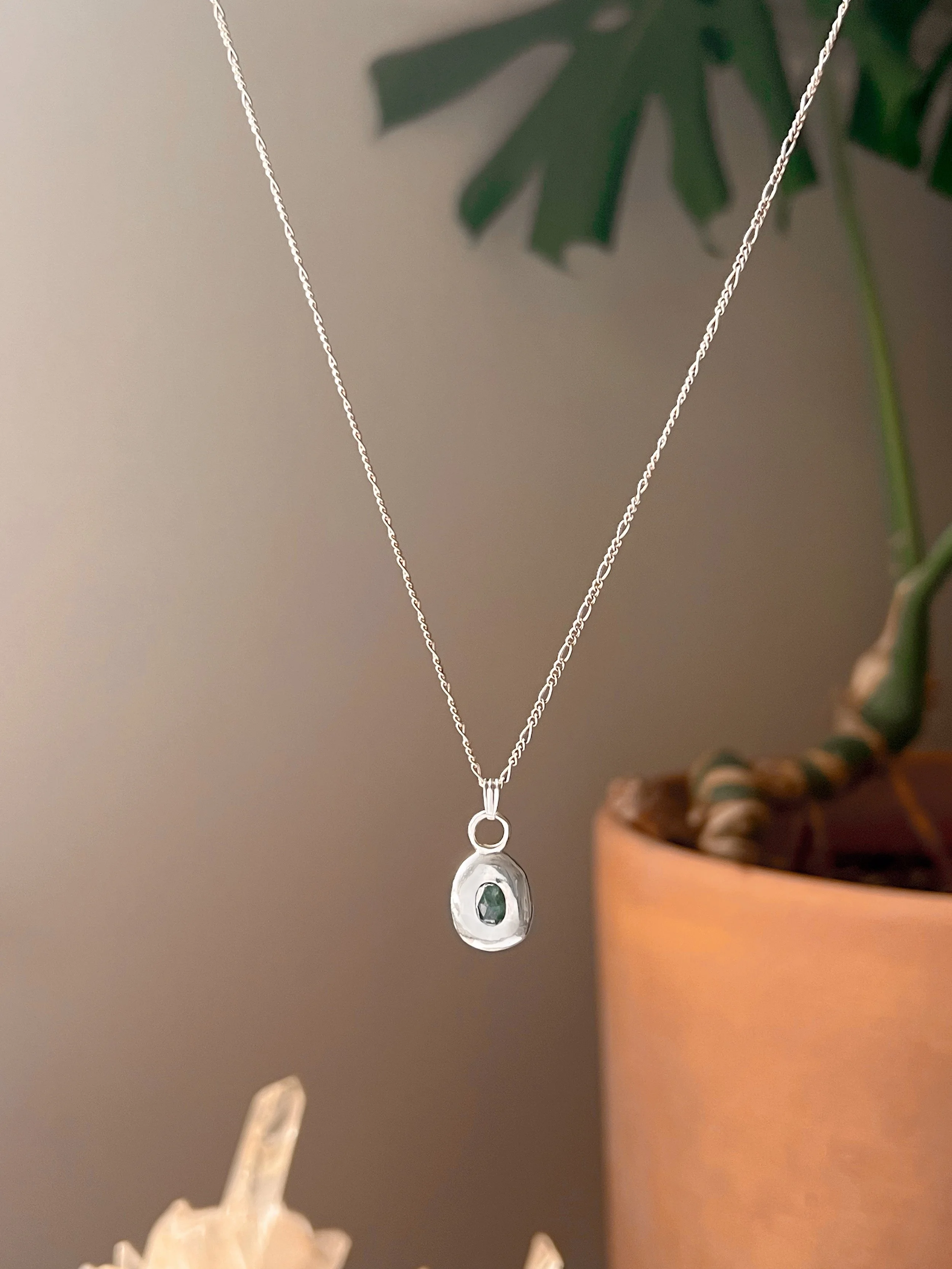 A recycled sterling silver blob, with a faceted gemstone in the center.