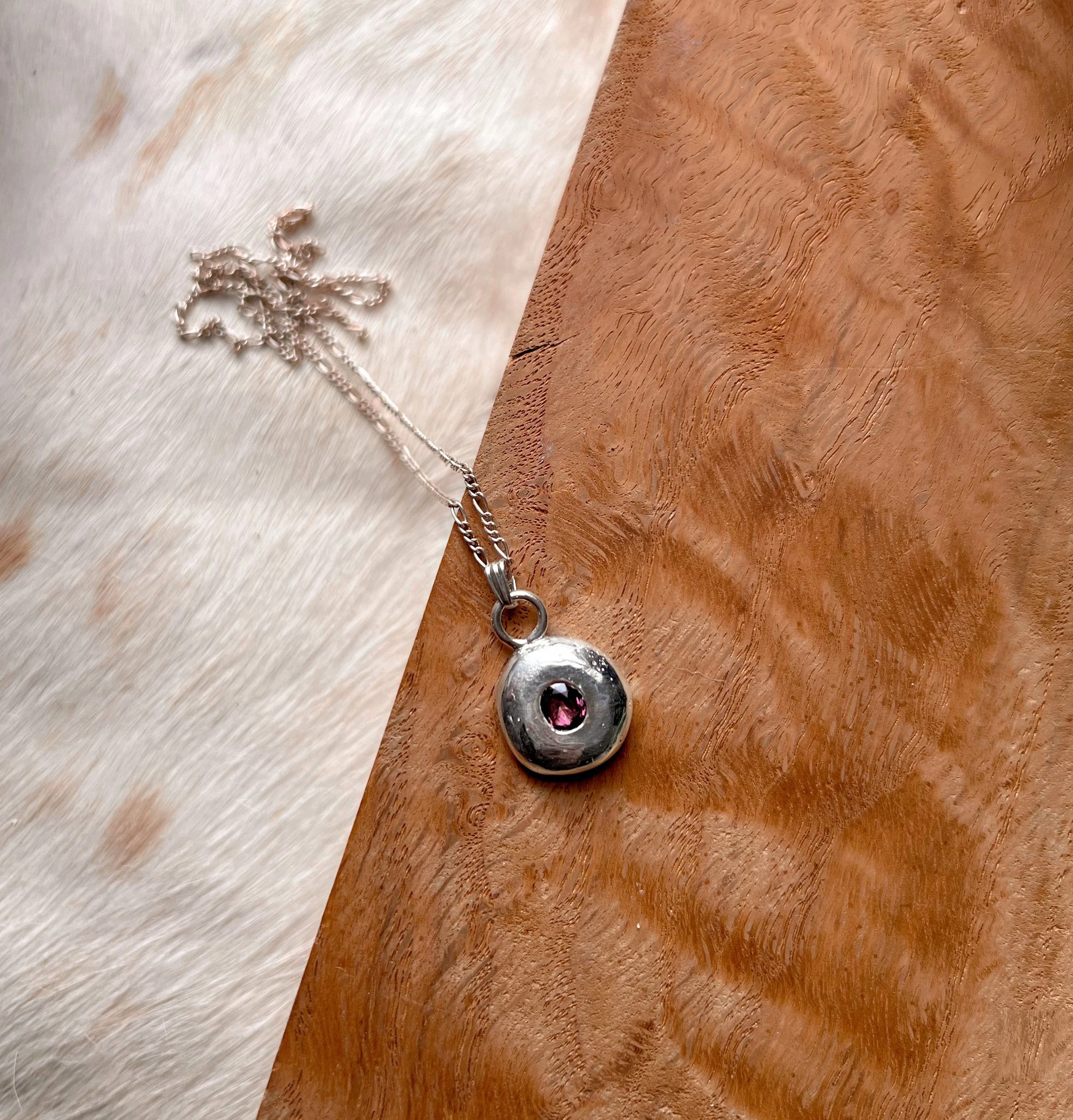 A recycled sterling silver blob, with a faceted gemstone in the center.