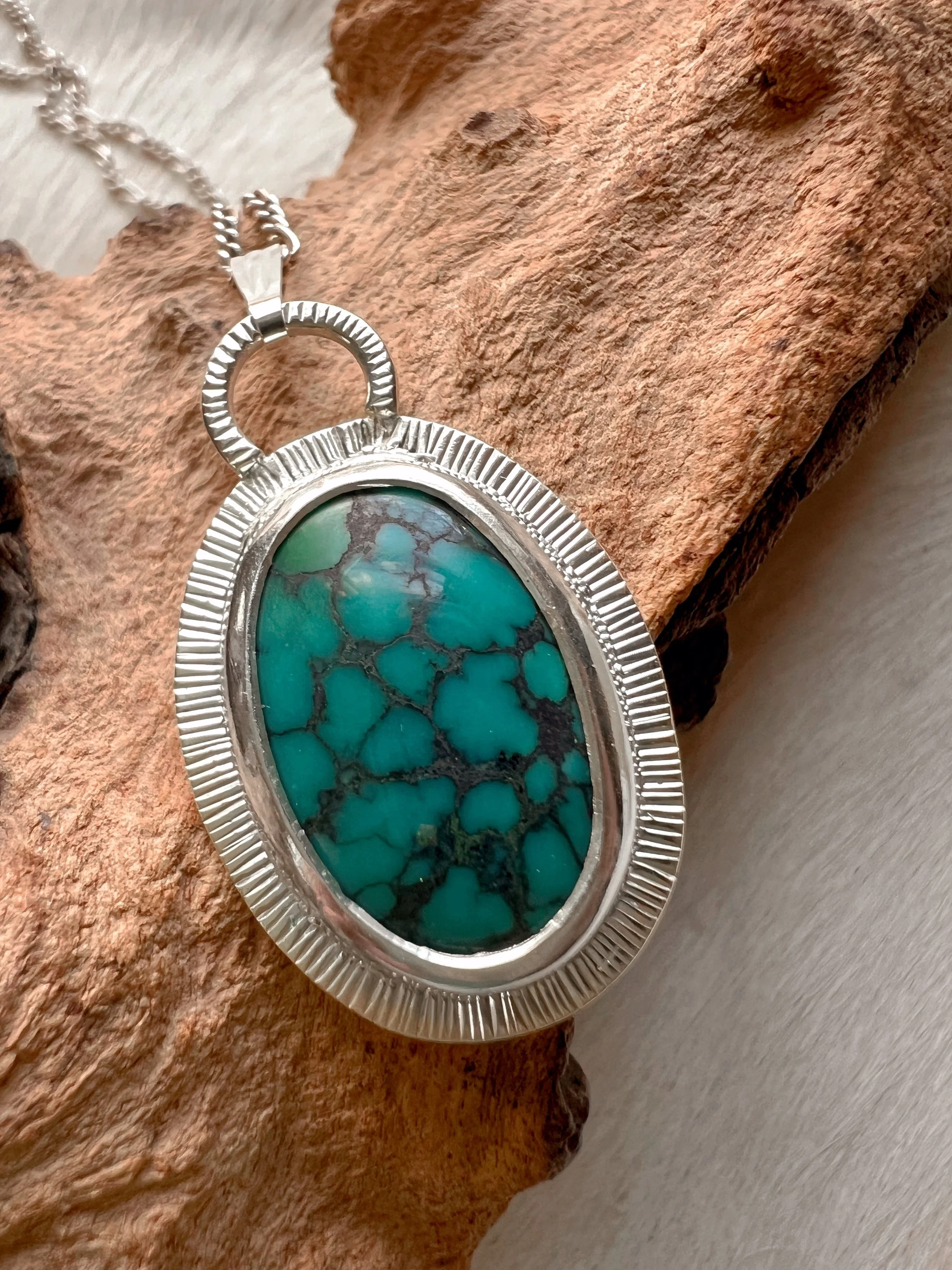 A smooth, natural gemstone cabochon set in a Sterling silver pendant on a sterling silver chain