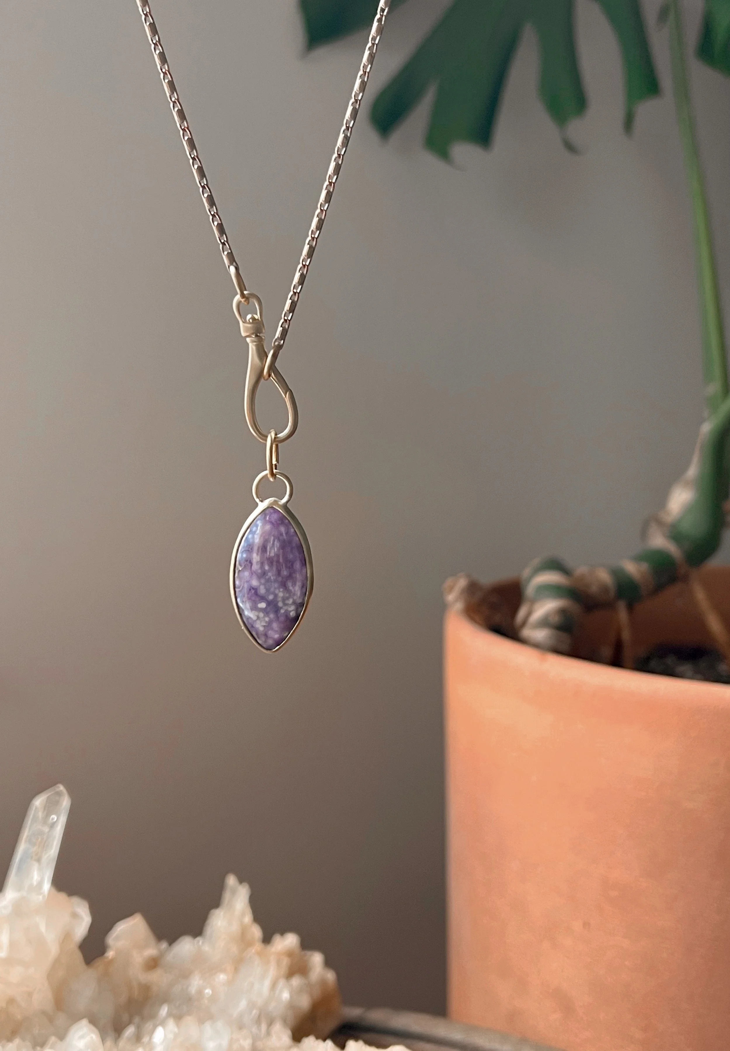 A smooth, natural gemstone cabochon set in a brass pendant on a brass chain.