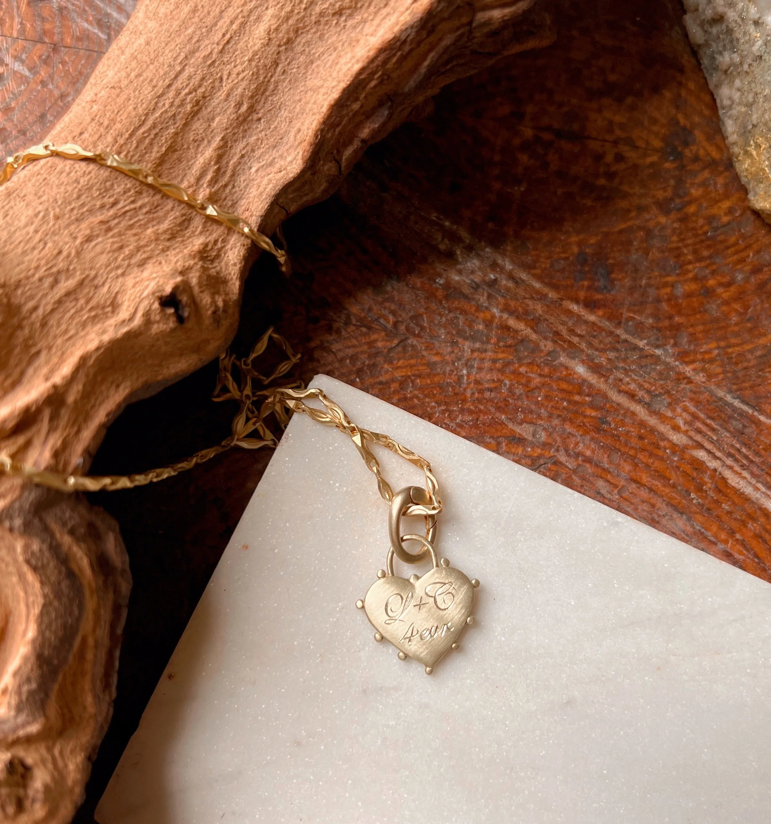 Personalized hand engraved script initials on a small brass heart