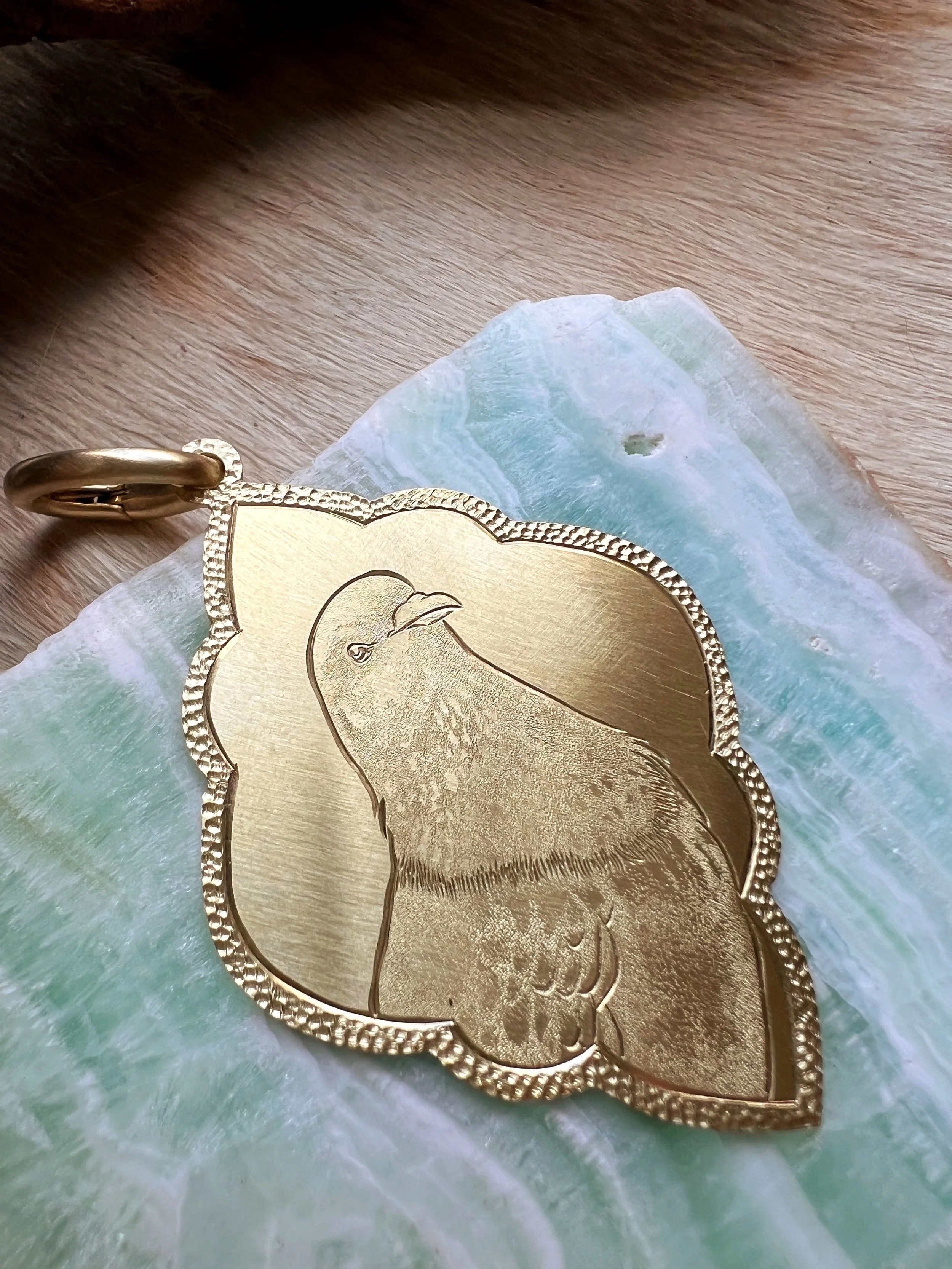 Detailed hand-engraved brass pendant featuring a bird portrait
