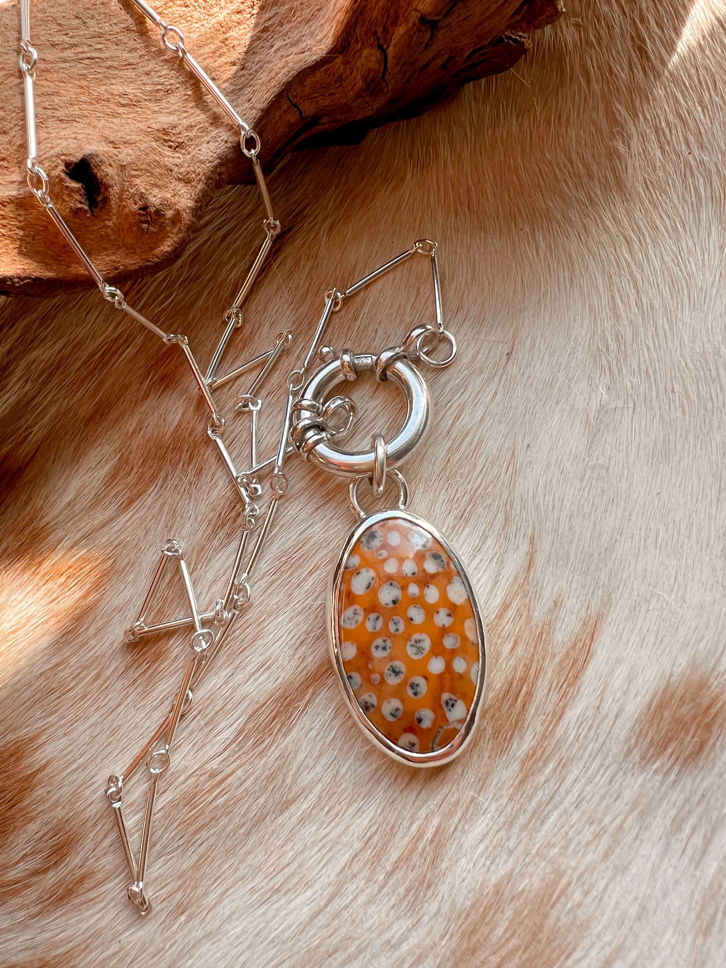 A smooth, natural gemstone cabochon set in a Sterling silver pendant on a sterling silver chain
