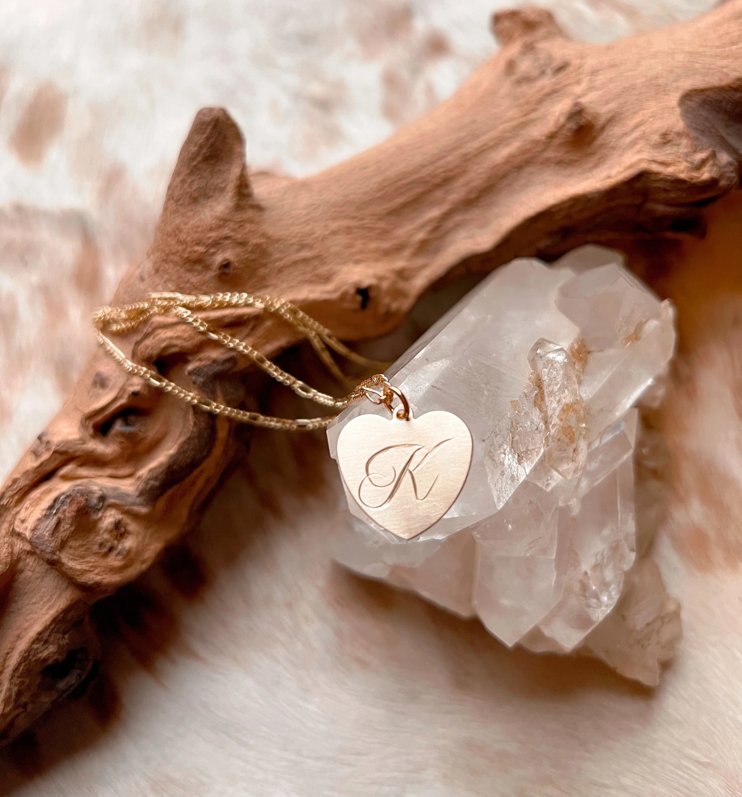 Personalized hand engraved script initial on a small brass heart