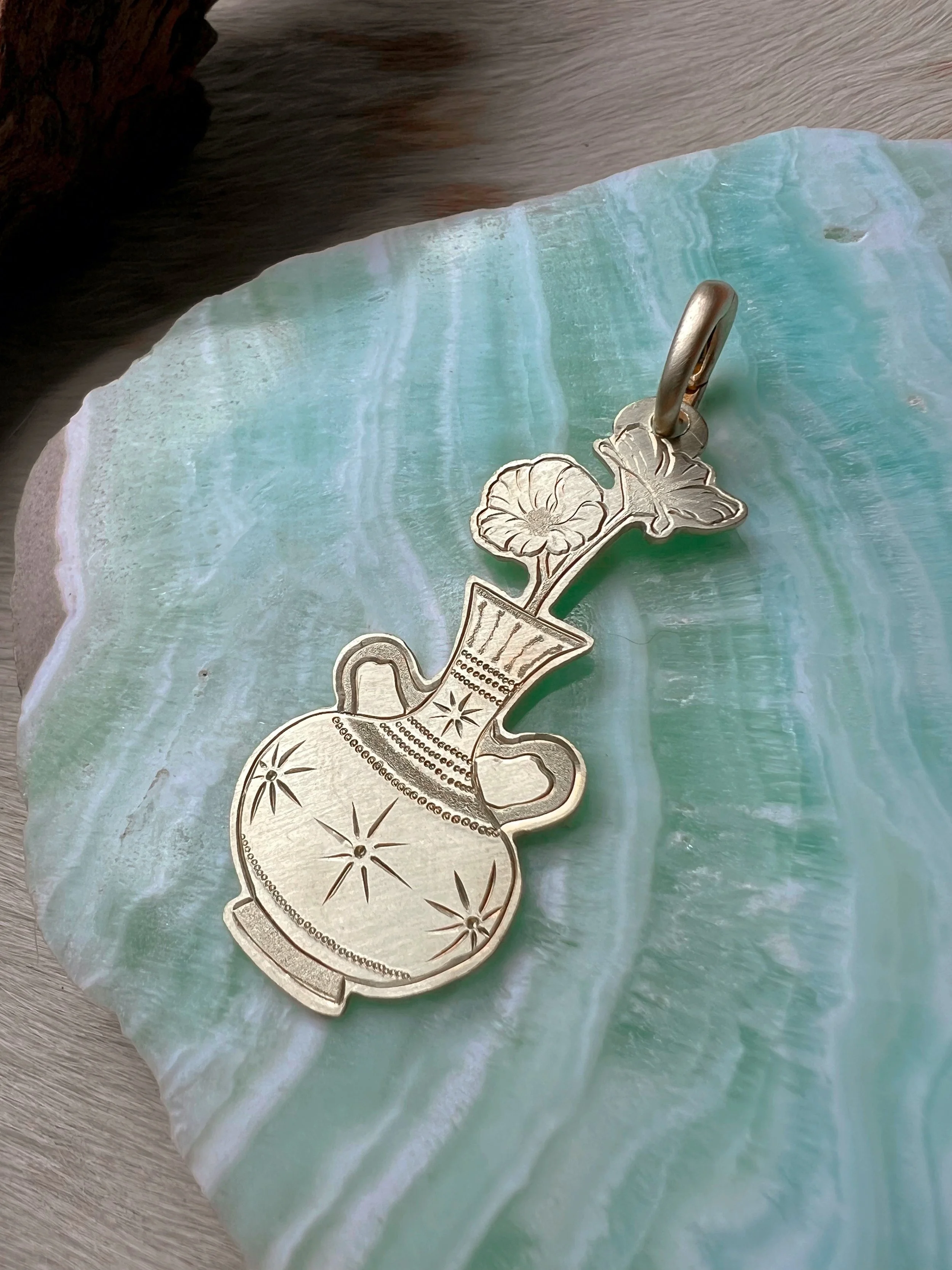 Detailed hand-engraved brass pendant featuring a Vase & flowers