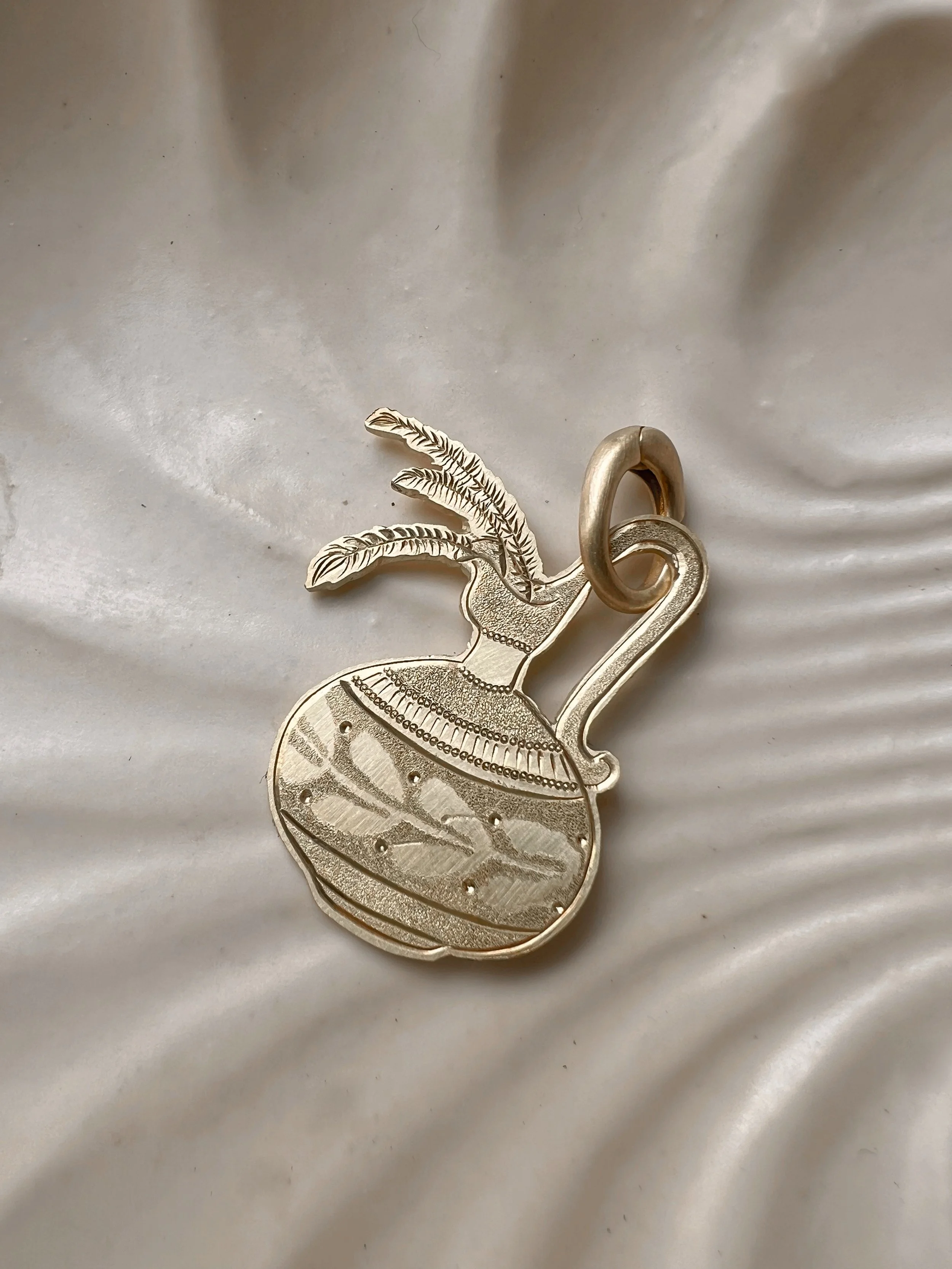 Detailed hand-engraved brass pendant featuring a Vase & flowers