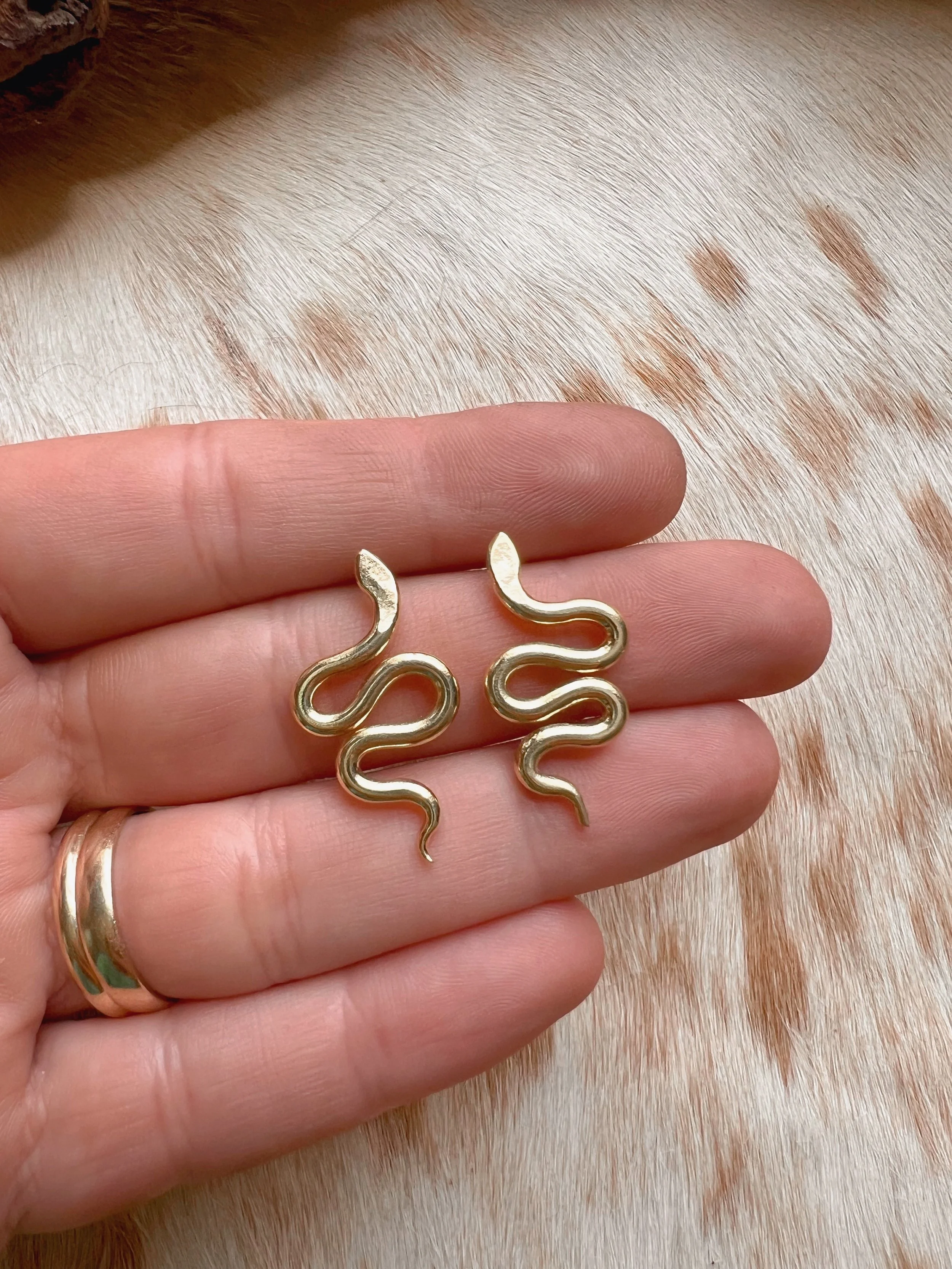 A pair of snake earrings made of brass with sterling silver posts and backs
