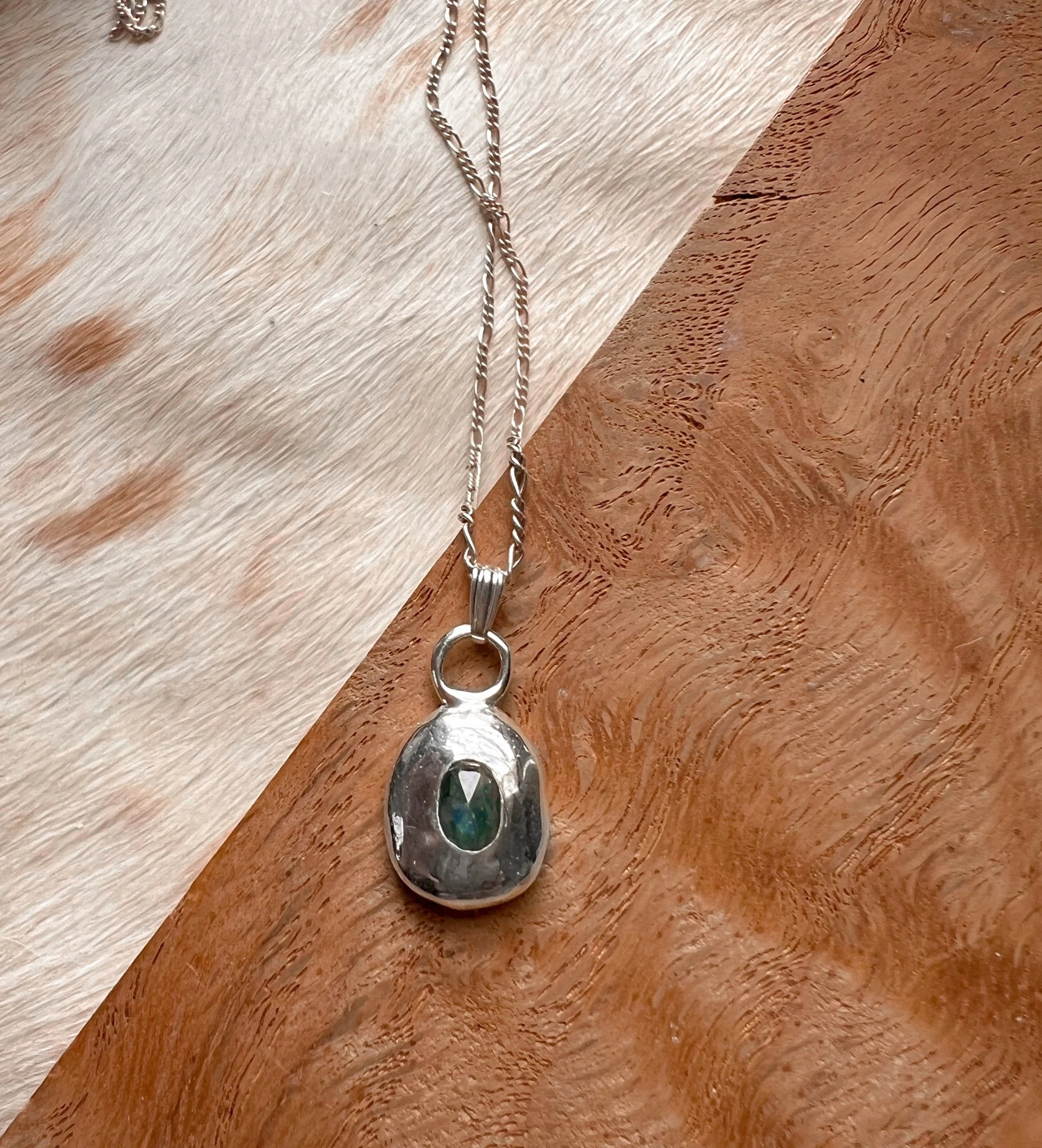 A recycled sterling silver blob, with a faceted gemstone in the center.