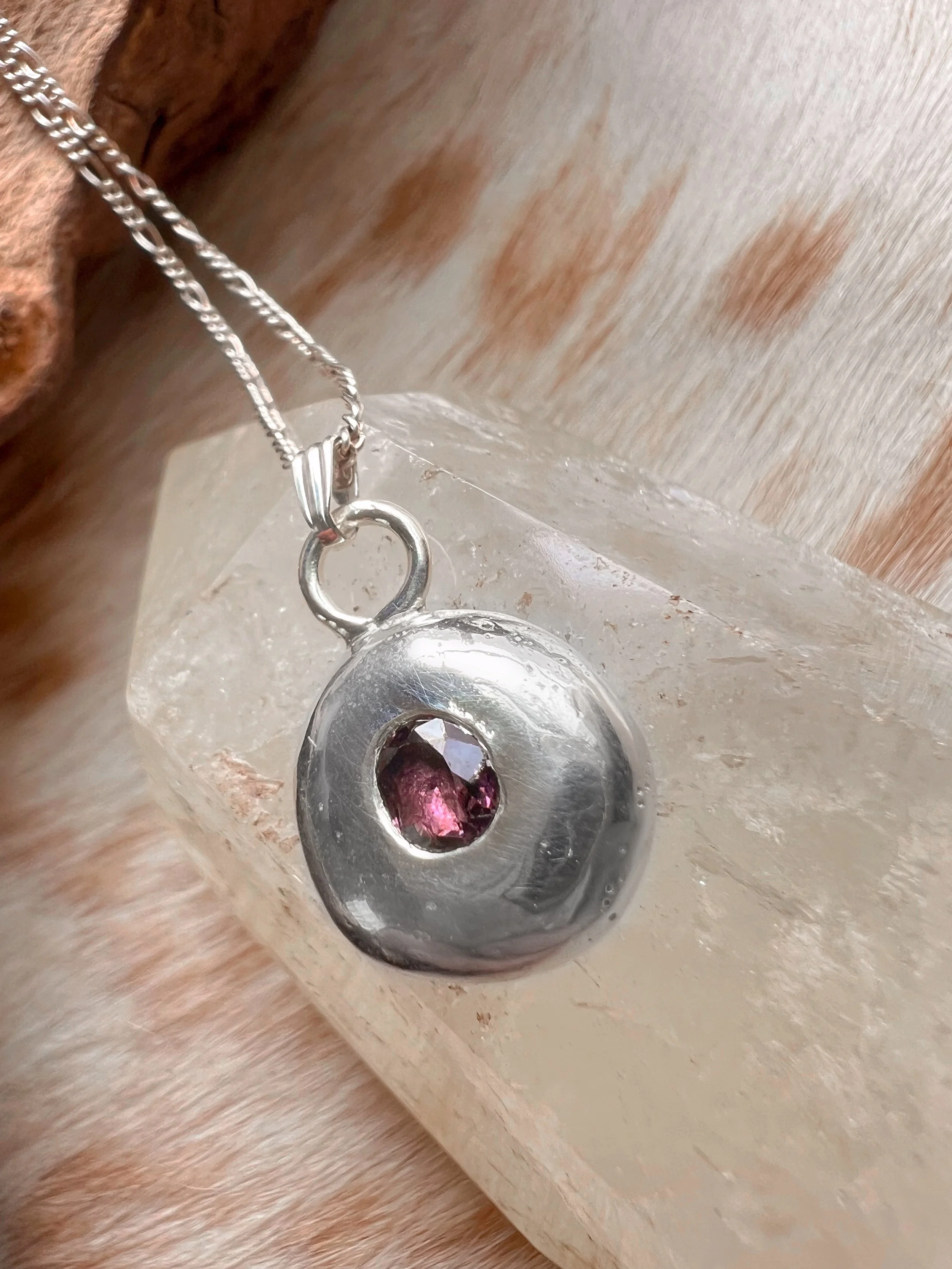 A recycled sterling silver blob, with a faceted gemstone in the center.