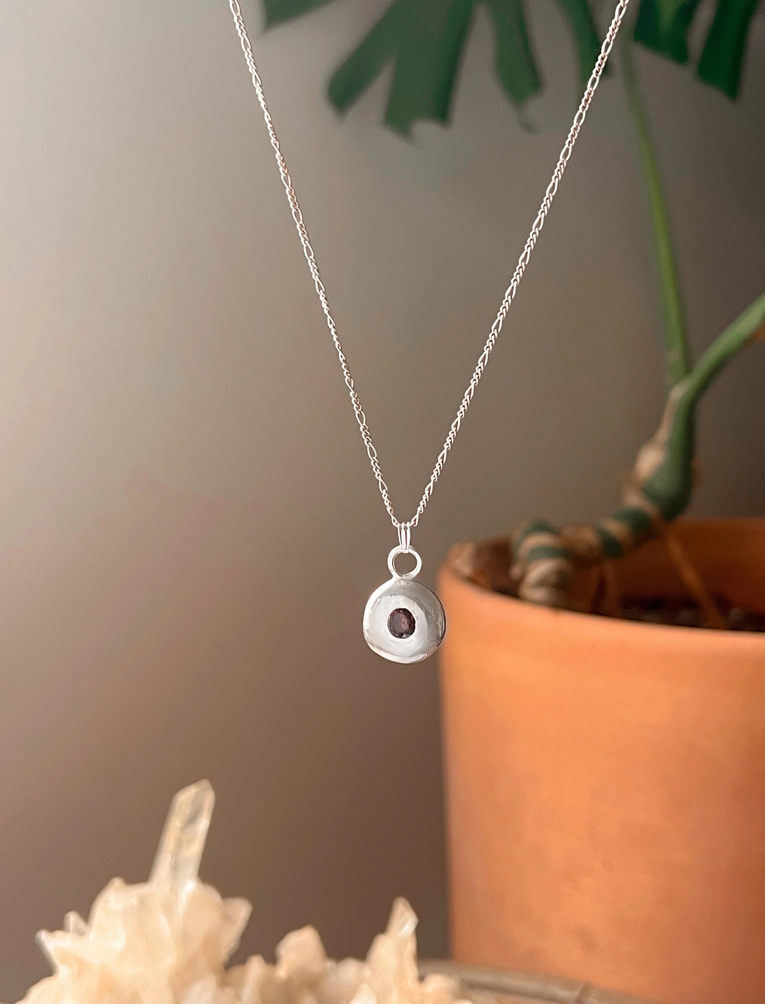 A recycled sterling silver blob, with a faceted gemstone in the center.