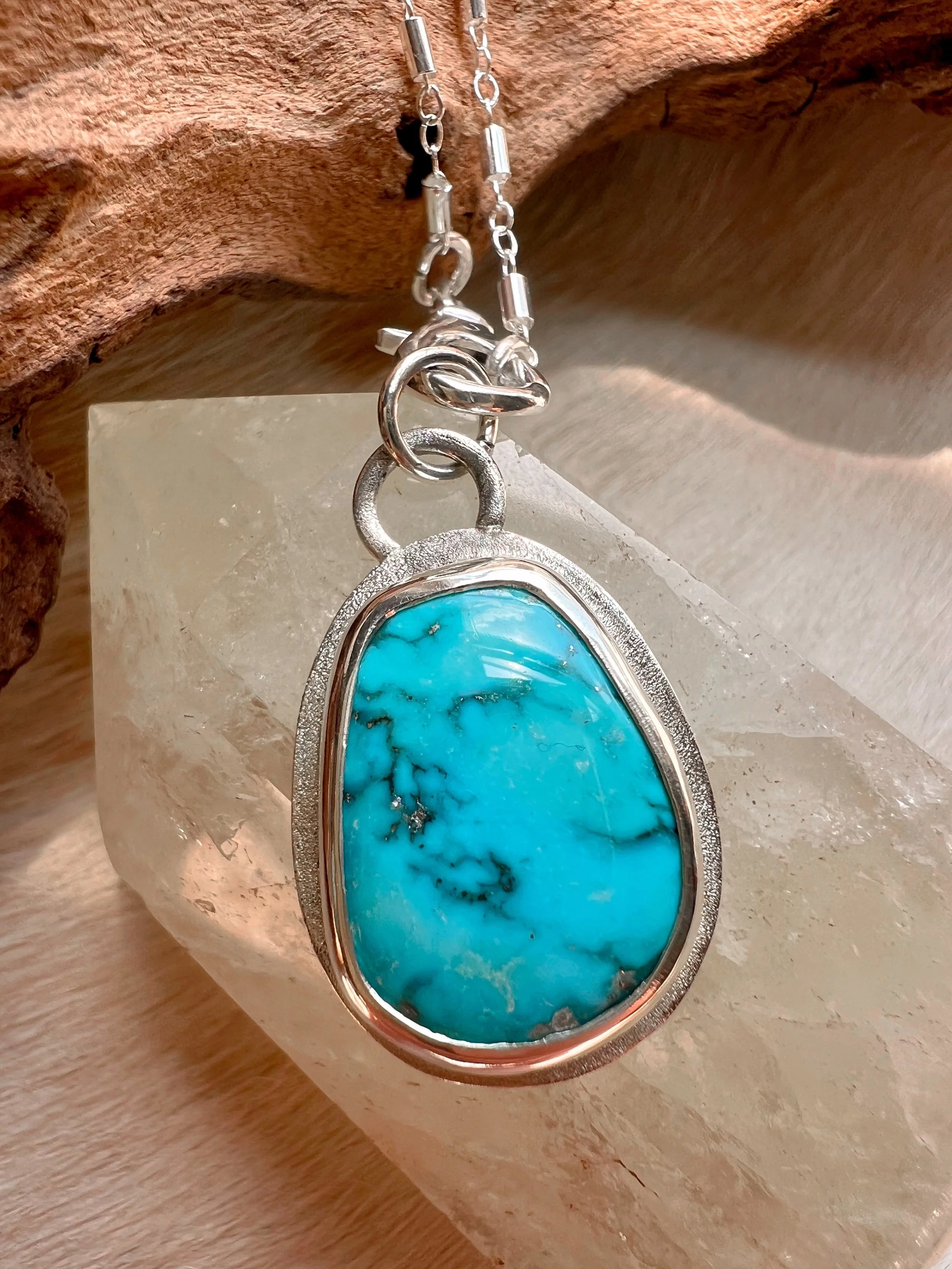 A smooth, natural gemstone cabochon set in a Sterling silver pendant on a sterling silver chain