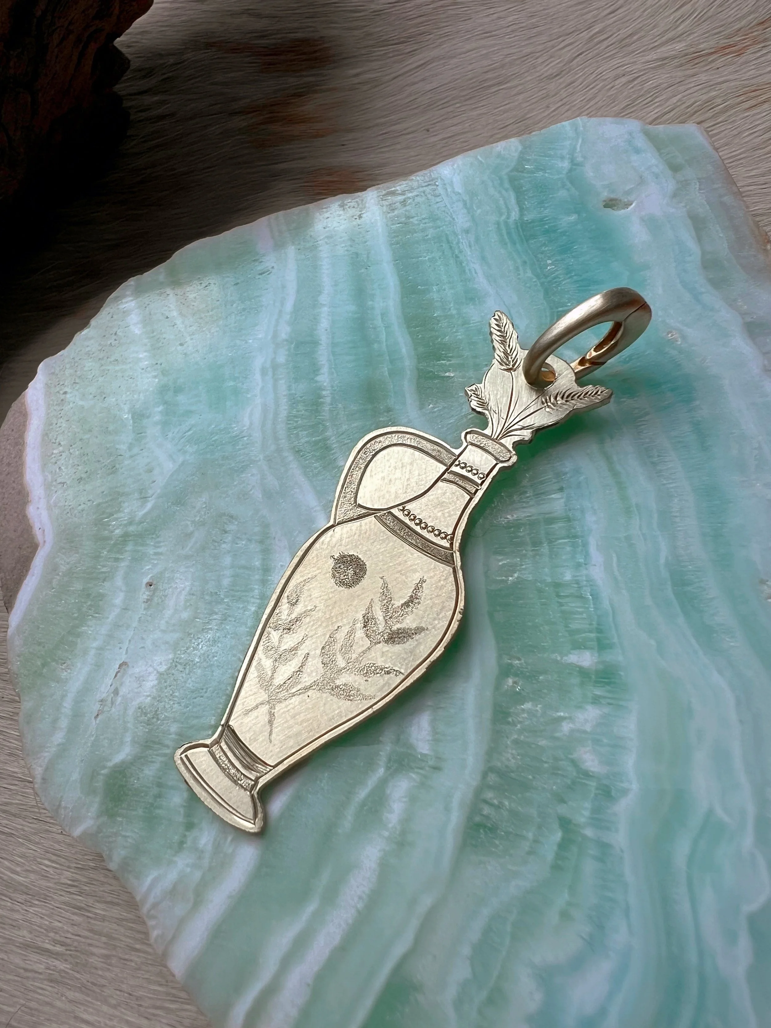 Detailed hand-engraved brass pendant featuring a Vase & flowers