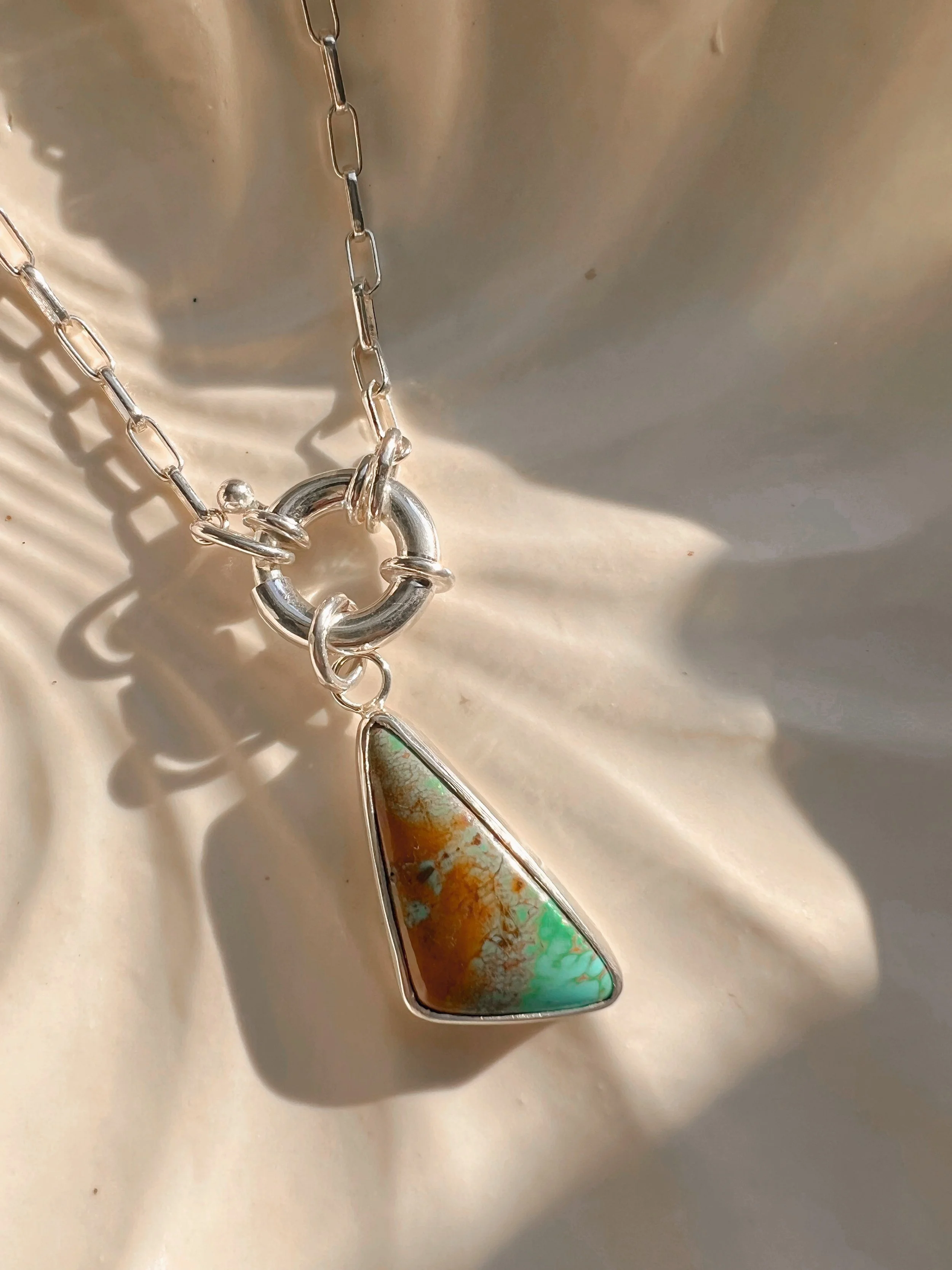 A smooth, natural gemstone cabochon set in a Sterling silver pendant on a sterling silver chain