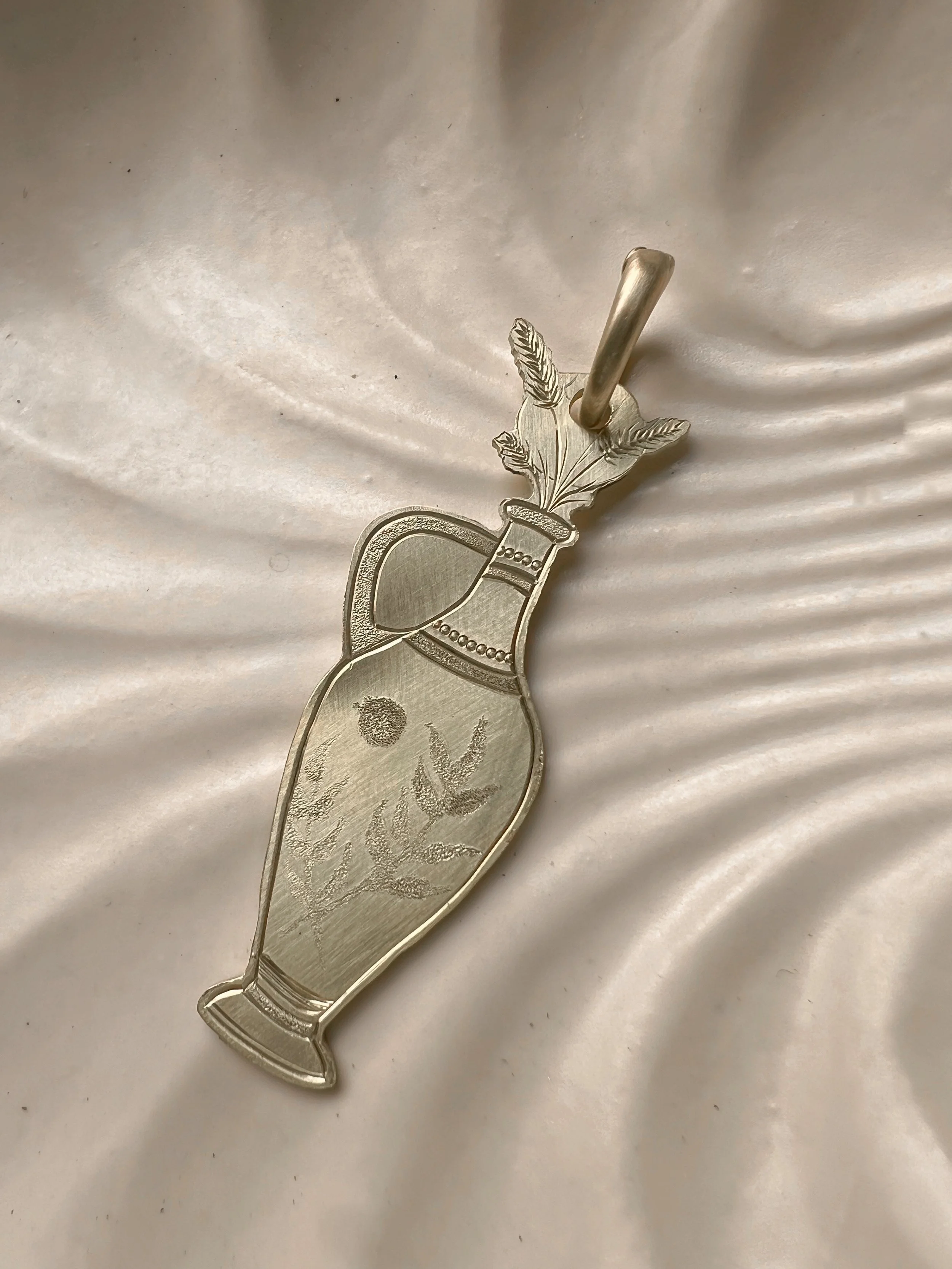 Detailed hand-engraved brass pendant featuring a Vase & flowers