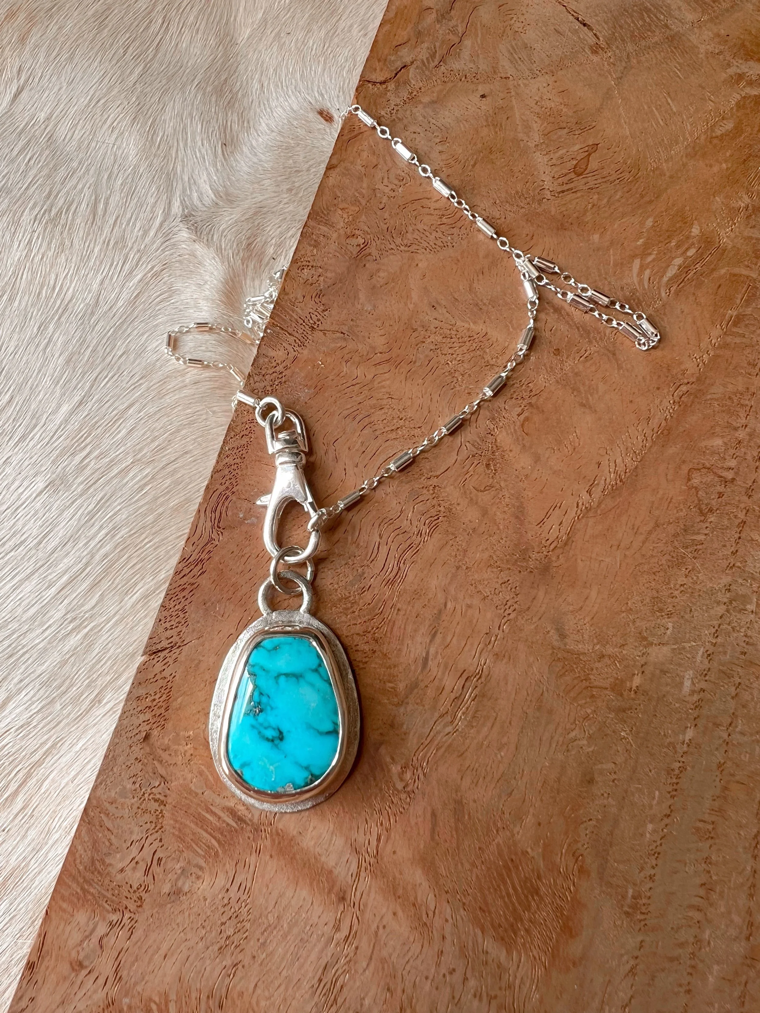 A smooth, natural gemstone cabochon set in a Sterling silver pendant on a sterling silver chain