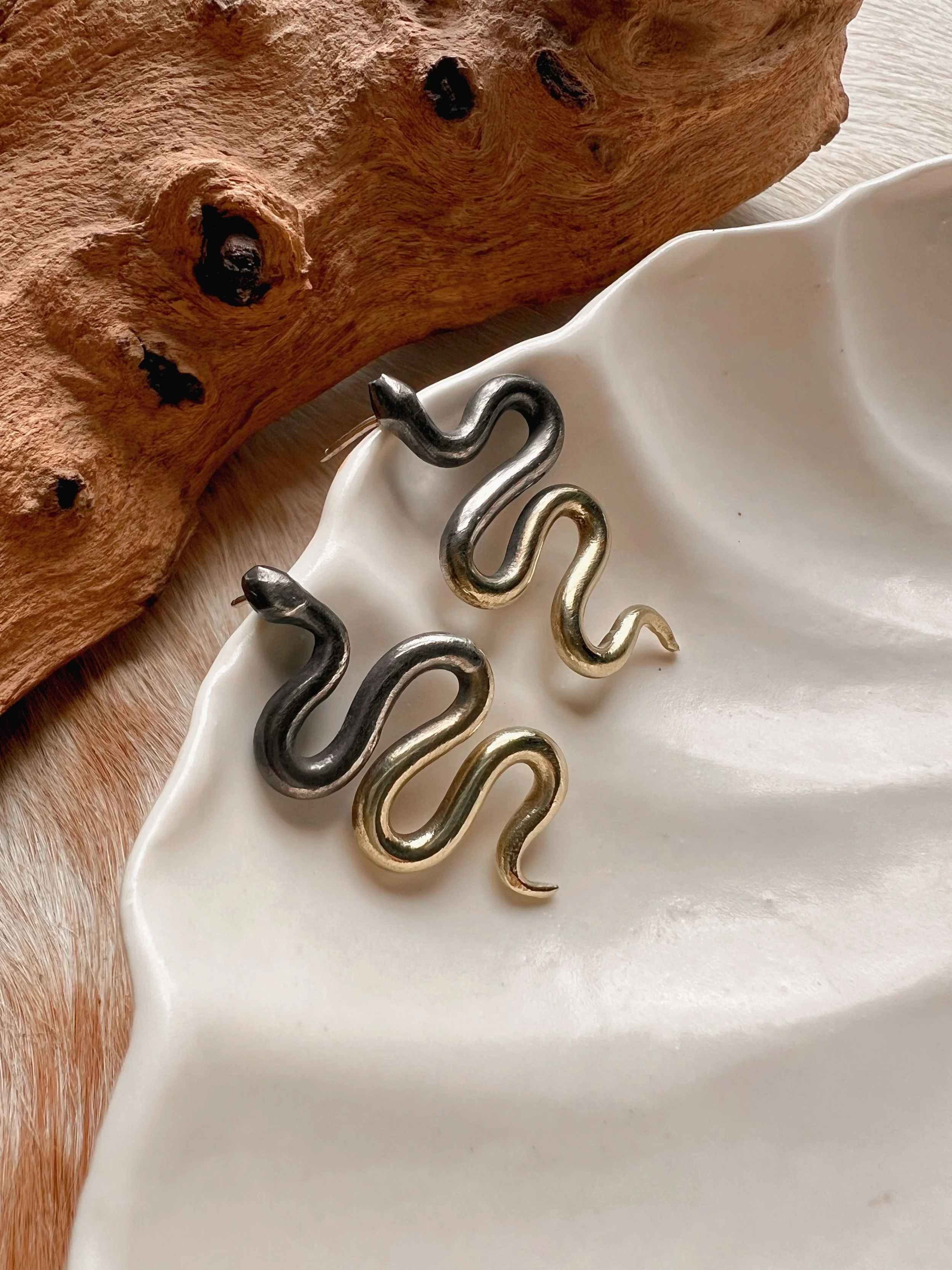 A pair of snake earrings made of oxidized silver fading to brass with sterling silver posts and backs